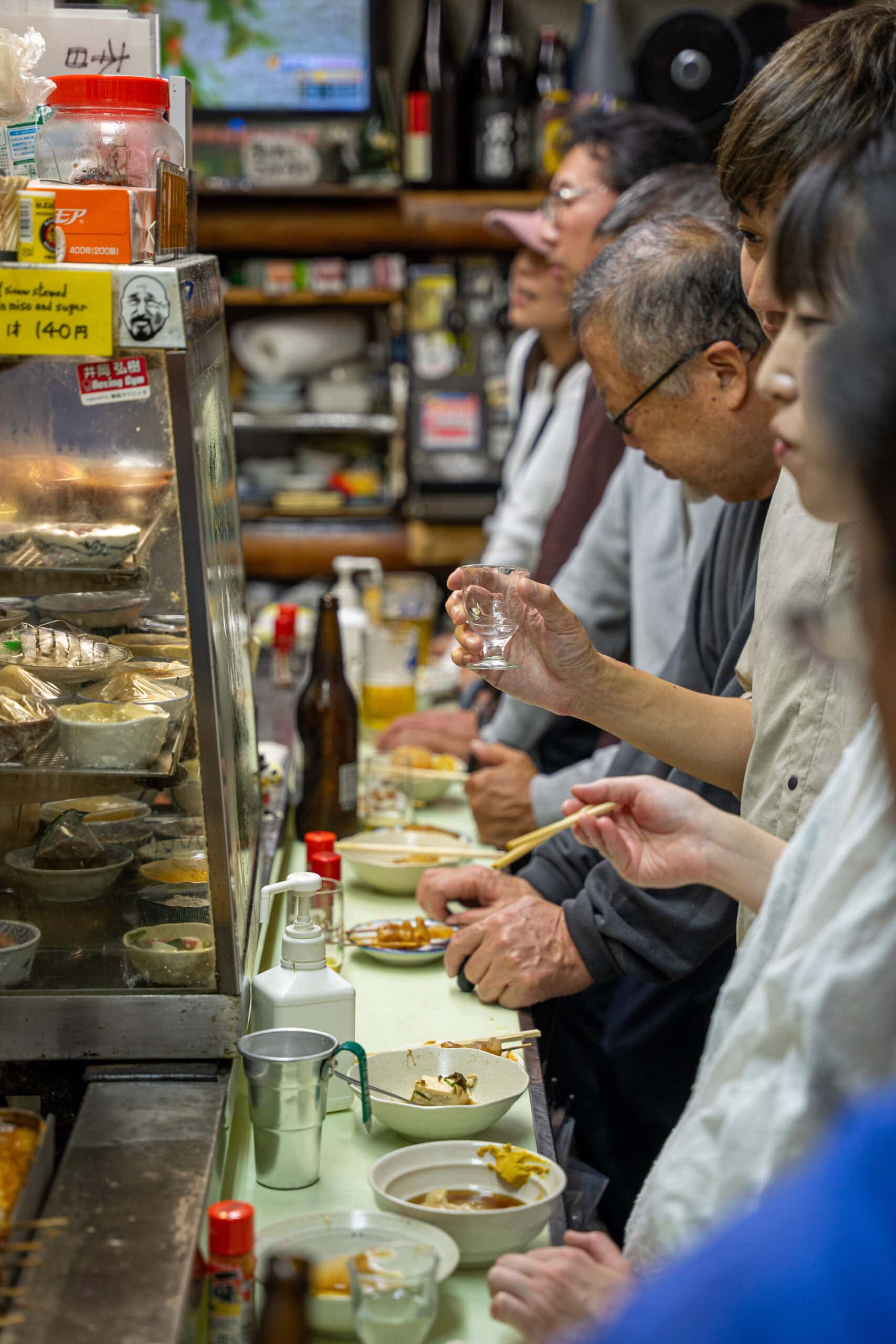 people stand shoulder to shoulder eating at Shinsekai 