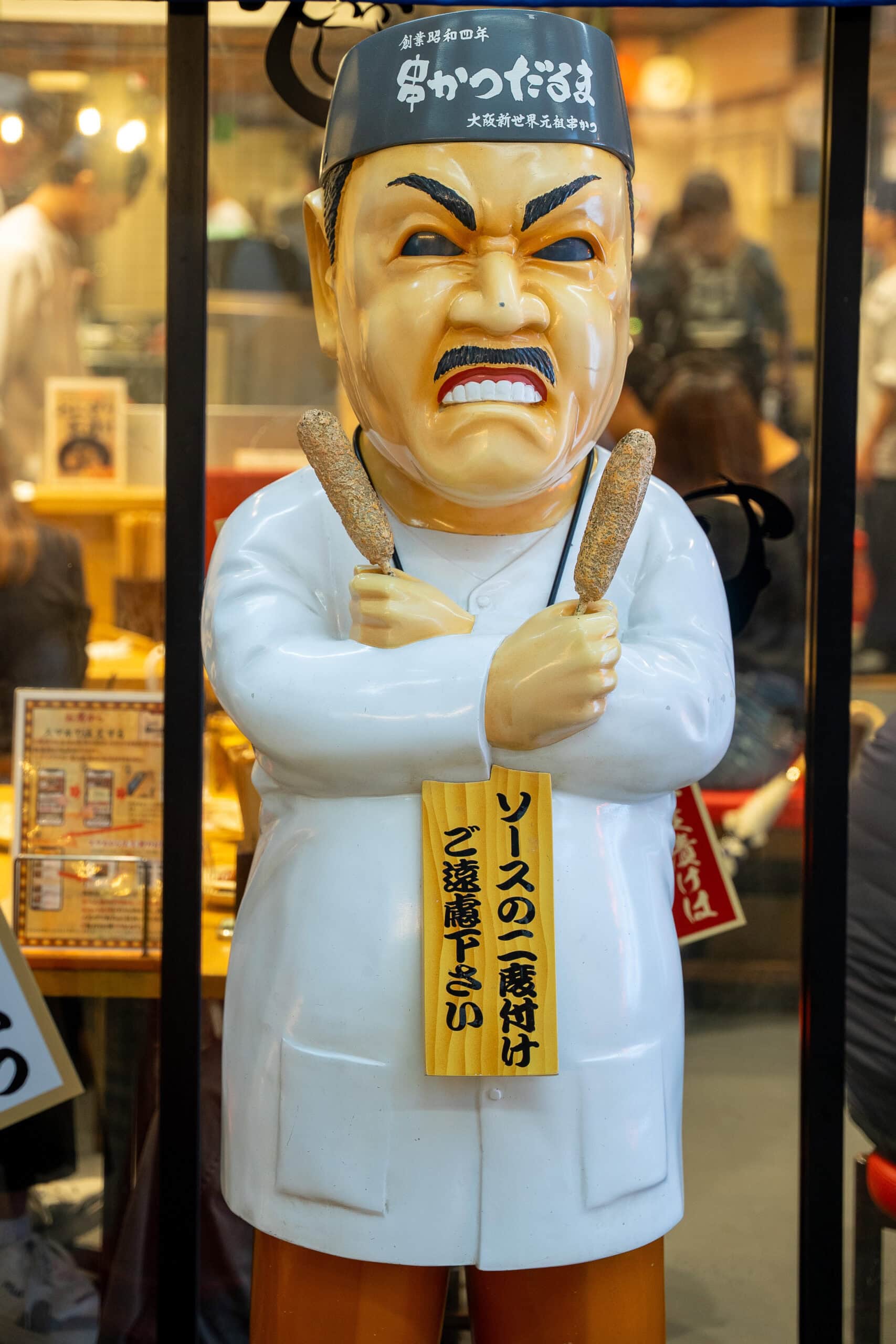 A statue of a chef standing outside a restaurant in Shinsekai  