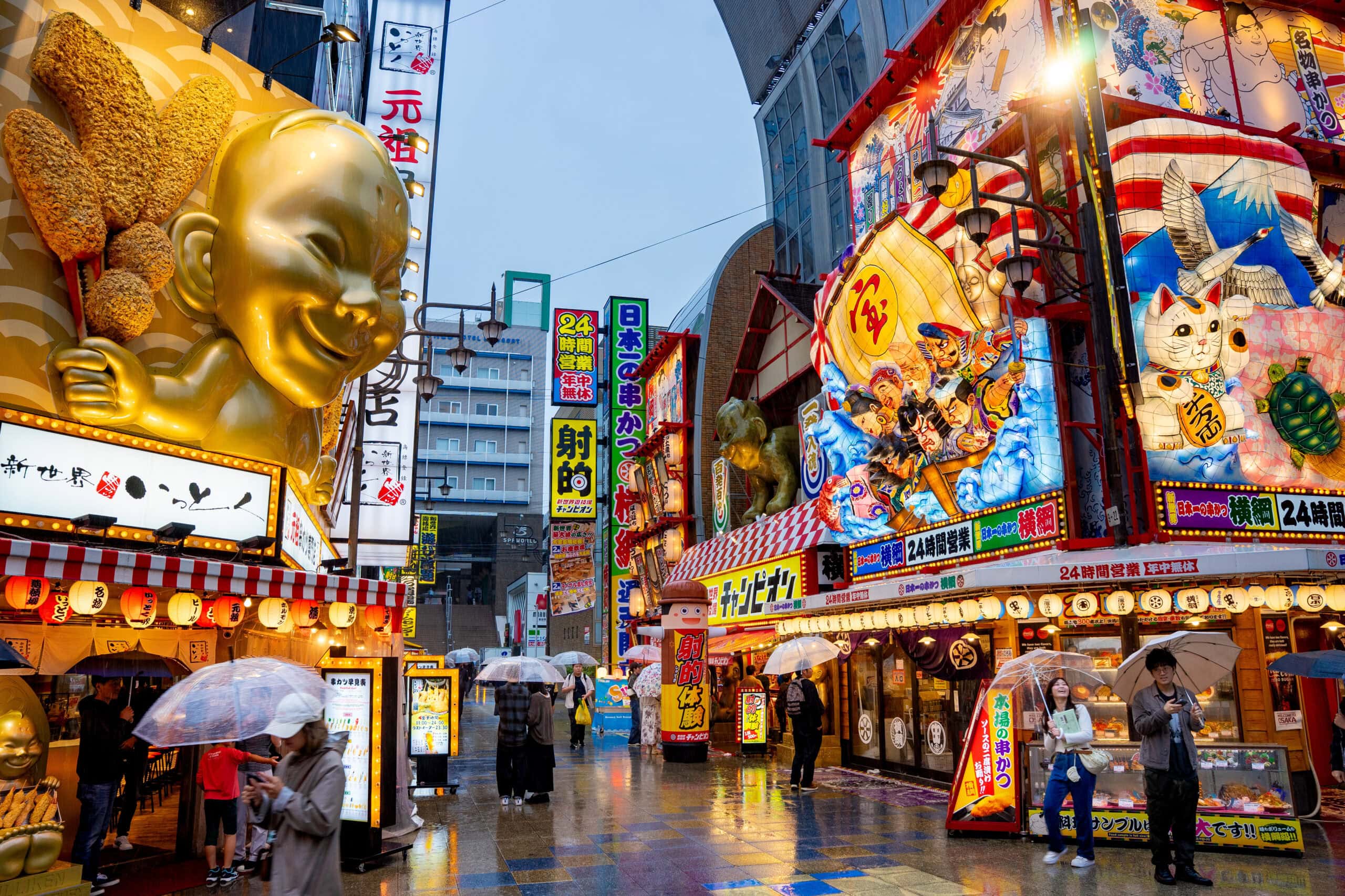 people stand under umbrellas in the rain at Shinsekai by day 