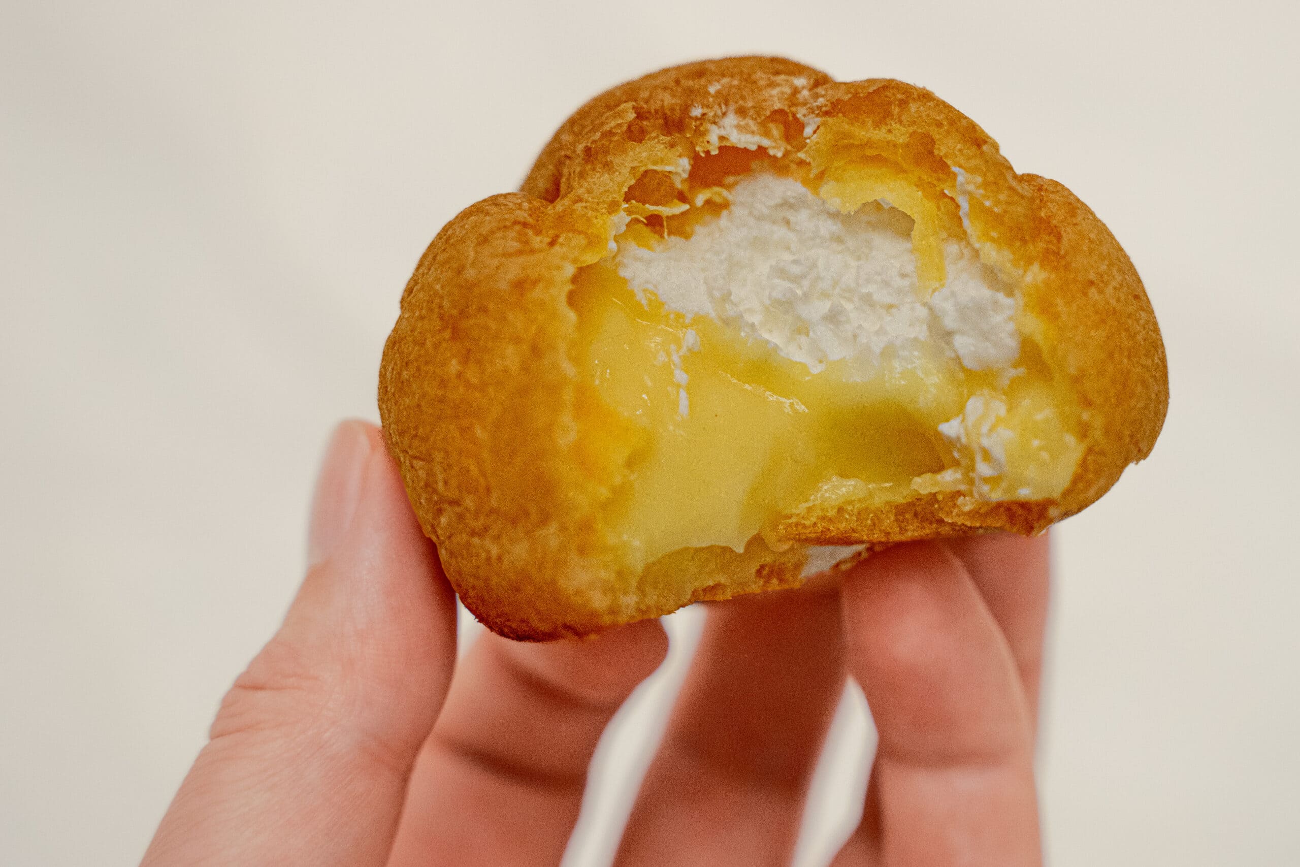 A cream puff I got from Lawson, bitten in half. You can see the puff is filled half with yellow custard and half with whipped cream