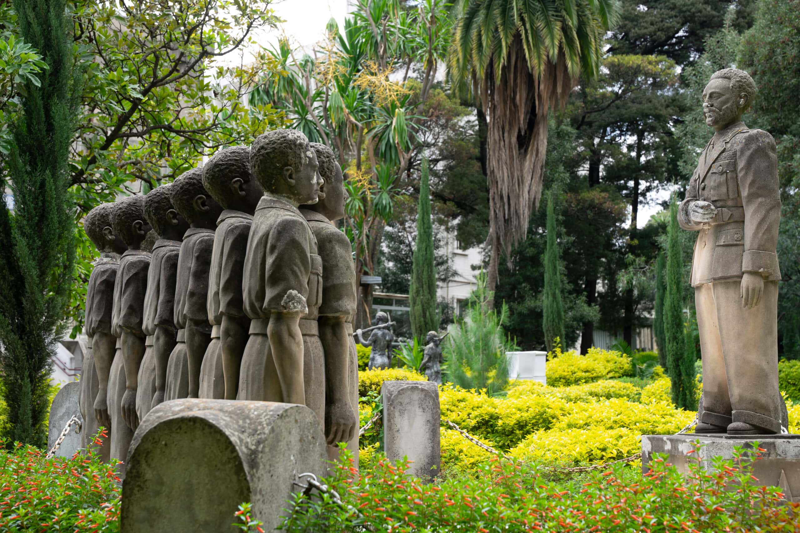 Statue of Haile Selassie addressing soldiers standing at attention in the garden of the National Museum of Ethiopia. The garden is lush and green