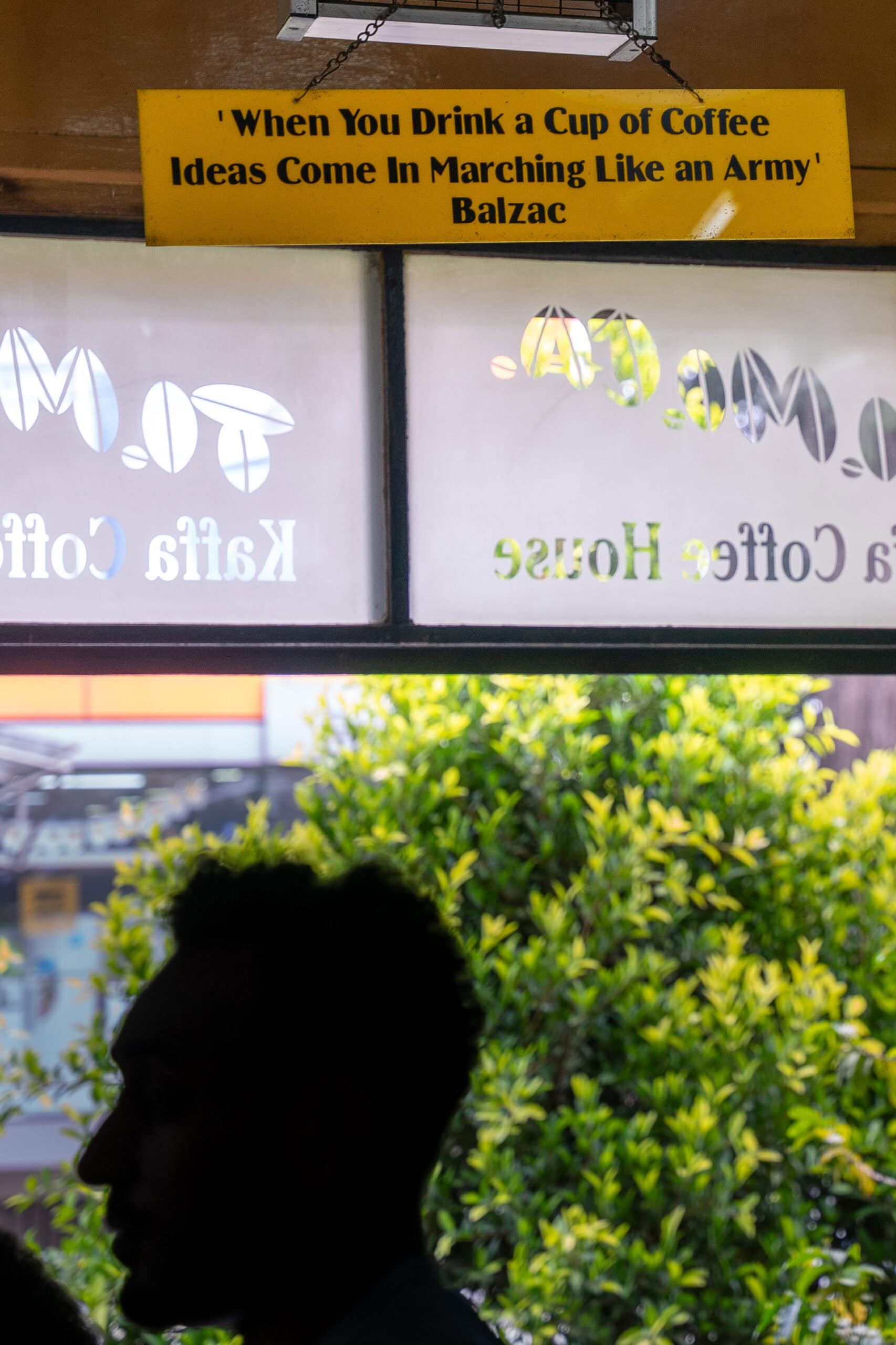 A yellow sign with a quote by Balzac saying:“When you drink a cup of coffee, ideas come in marching like an army”hangs inside Tomoca Coffee House in Addis Ababa