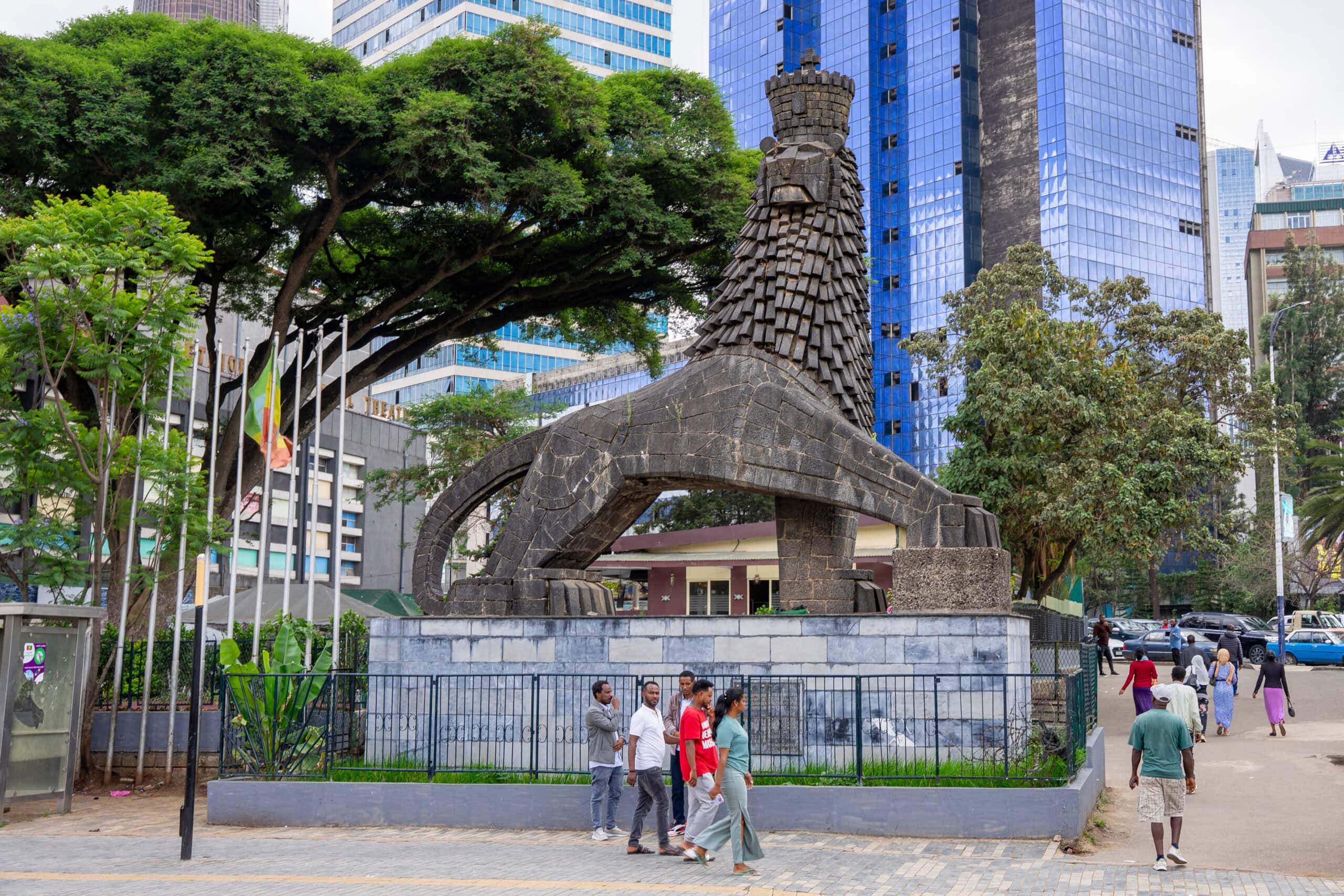 People walk in the side walk in central Addis Ababa, passing the Lion of Judah Monument