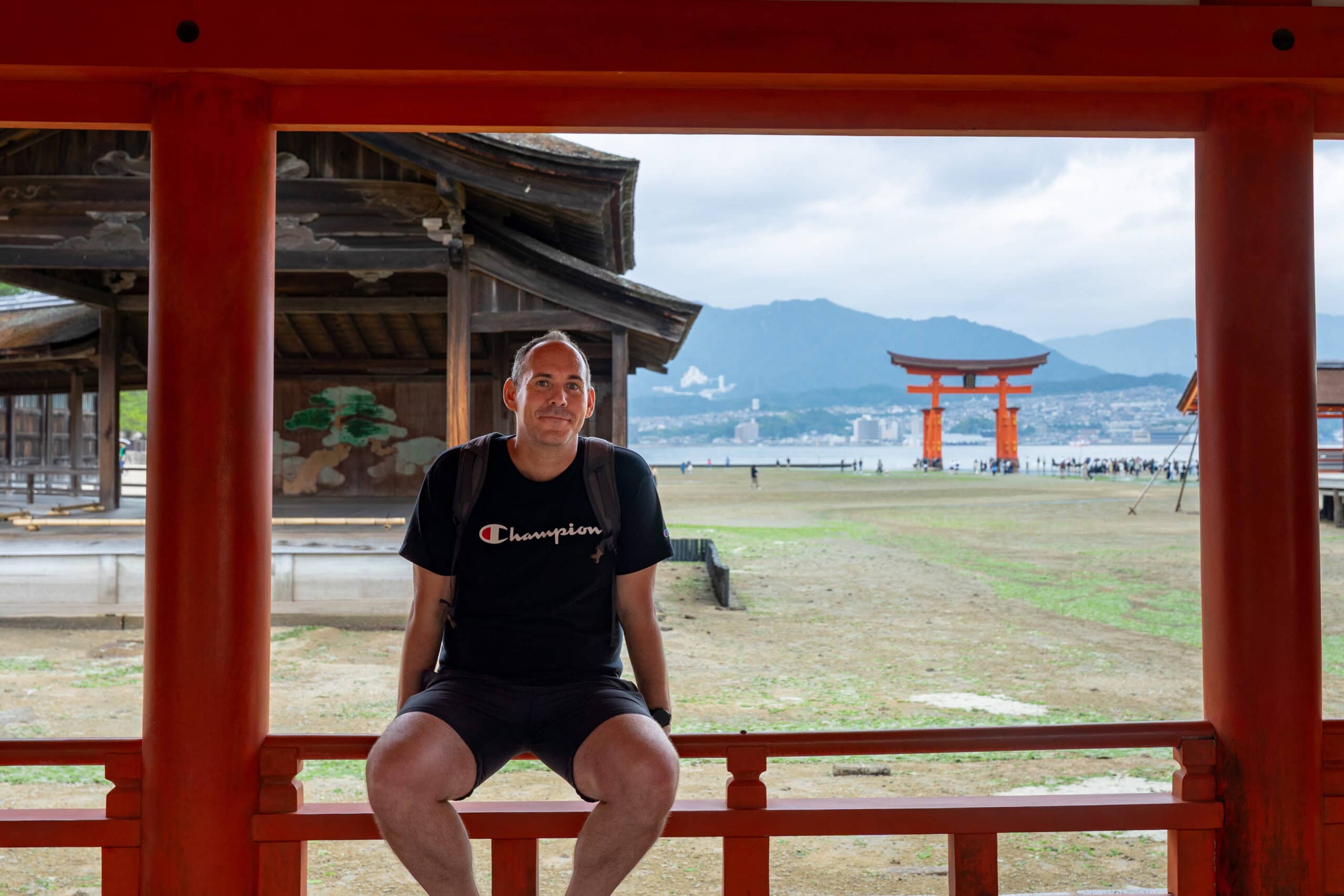 Im posing for a photo in a shrine on Miyajima island with the torii gate behind me