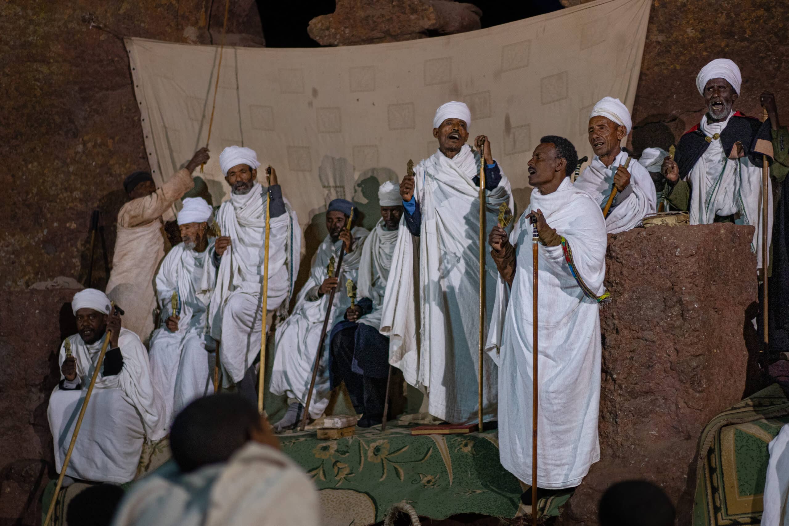 A group of men dressed in white sing in a rock-hewn church during Sunday morning Mass in Lalibela