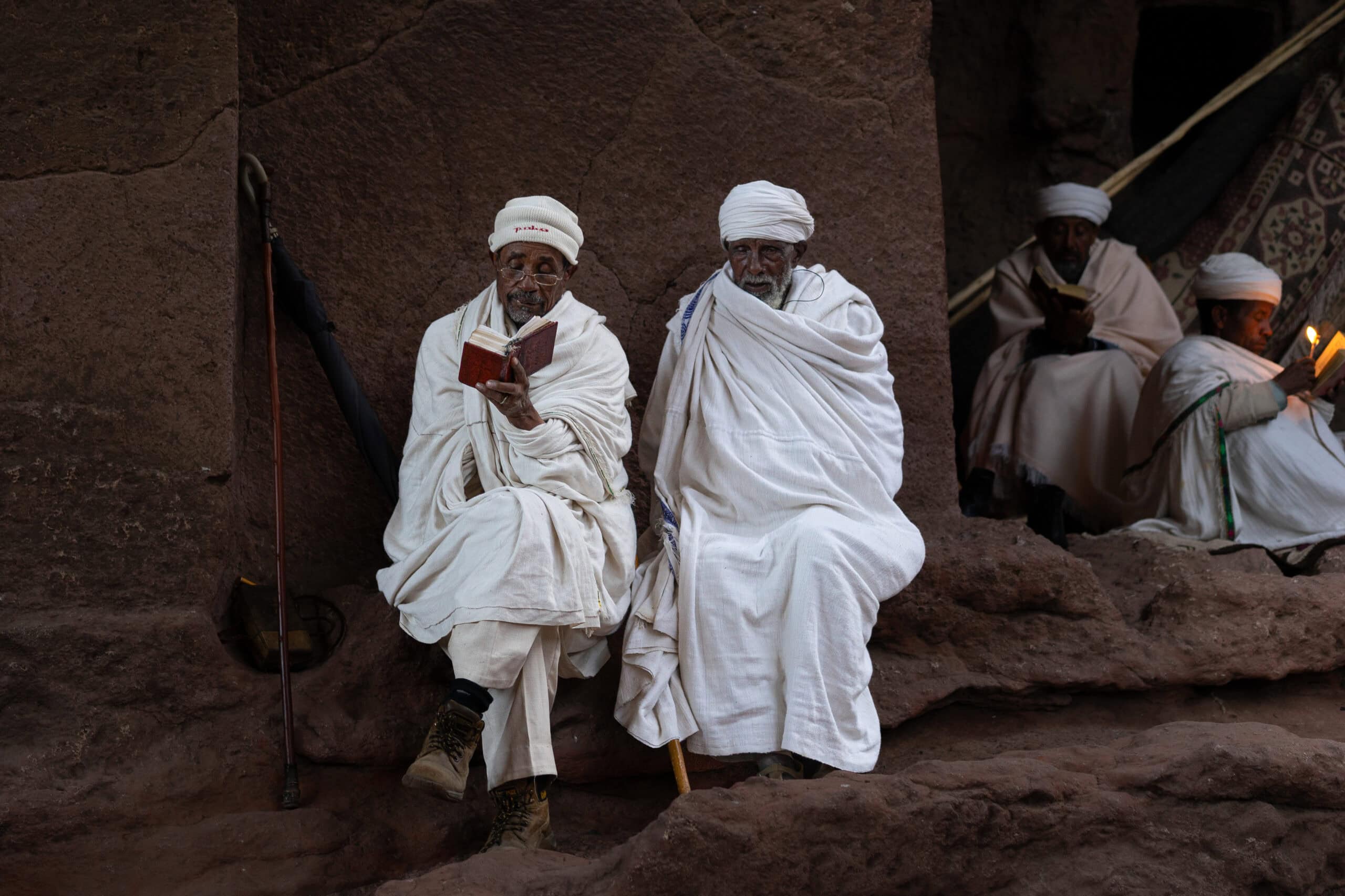 Two elderly men dressed in white sits and read bible during Sunday Mass in Lalibela, Ethiopia