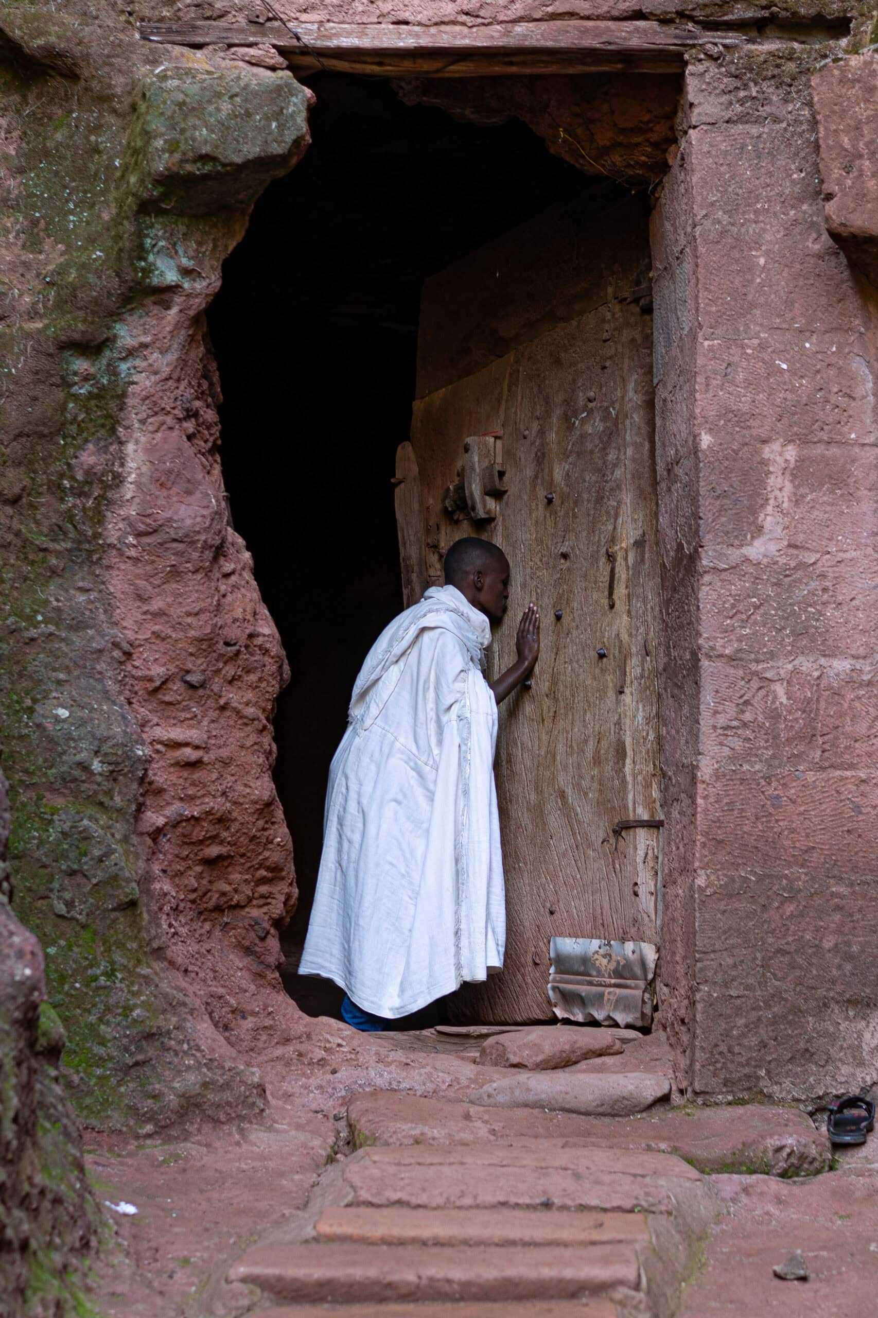 A woman kisses a wooden door at Biet Giyorgis, the church of Saint George, Lalibela