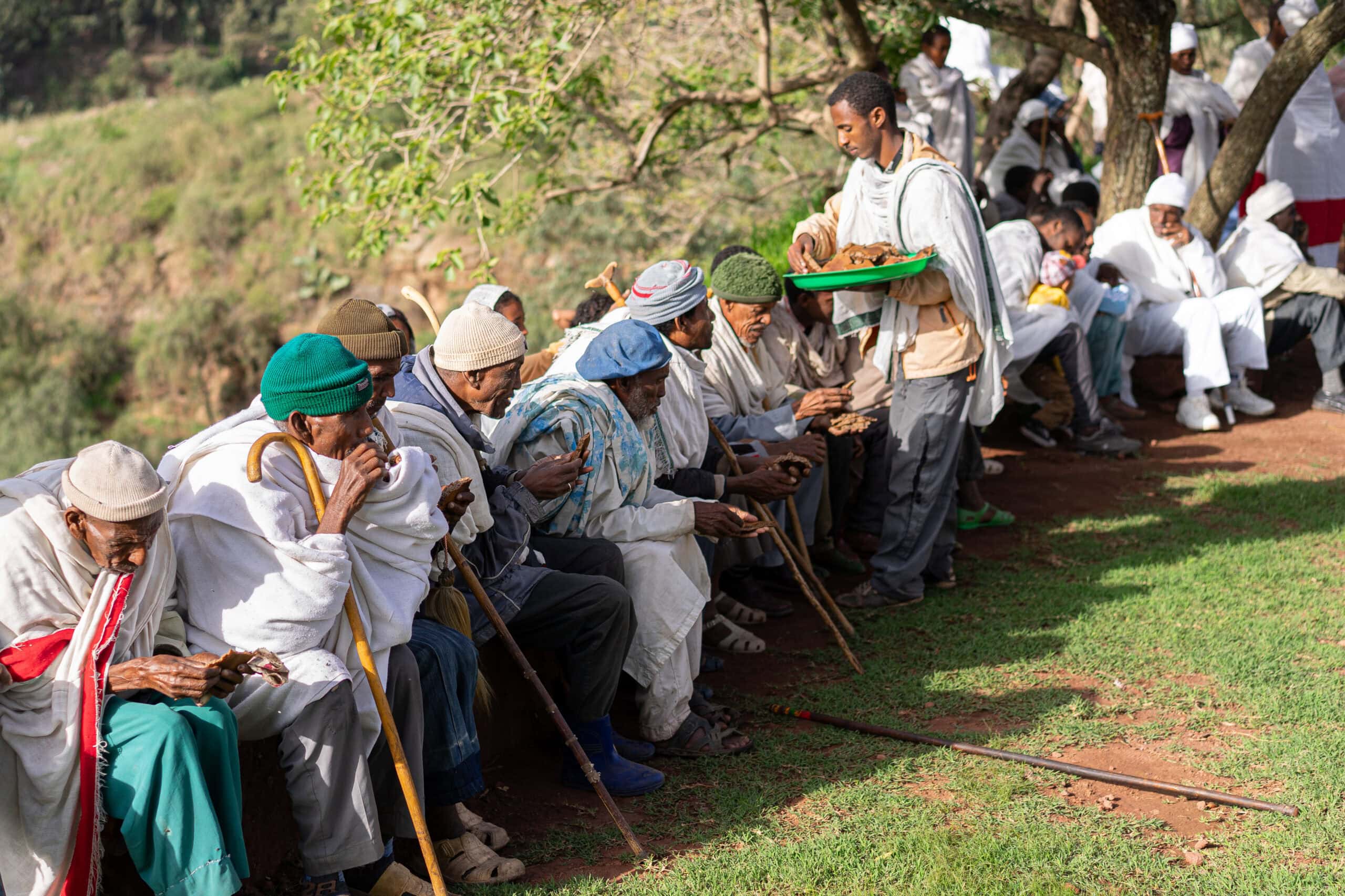 Church boys at Biet Giyorgis hand out injera to a group of men sitting in the morning sun after attending Sunday mass