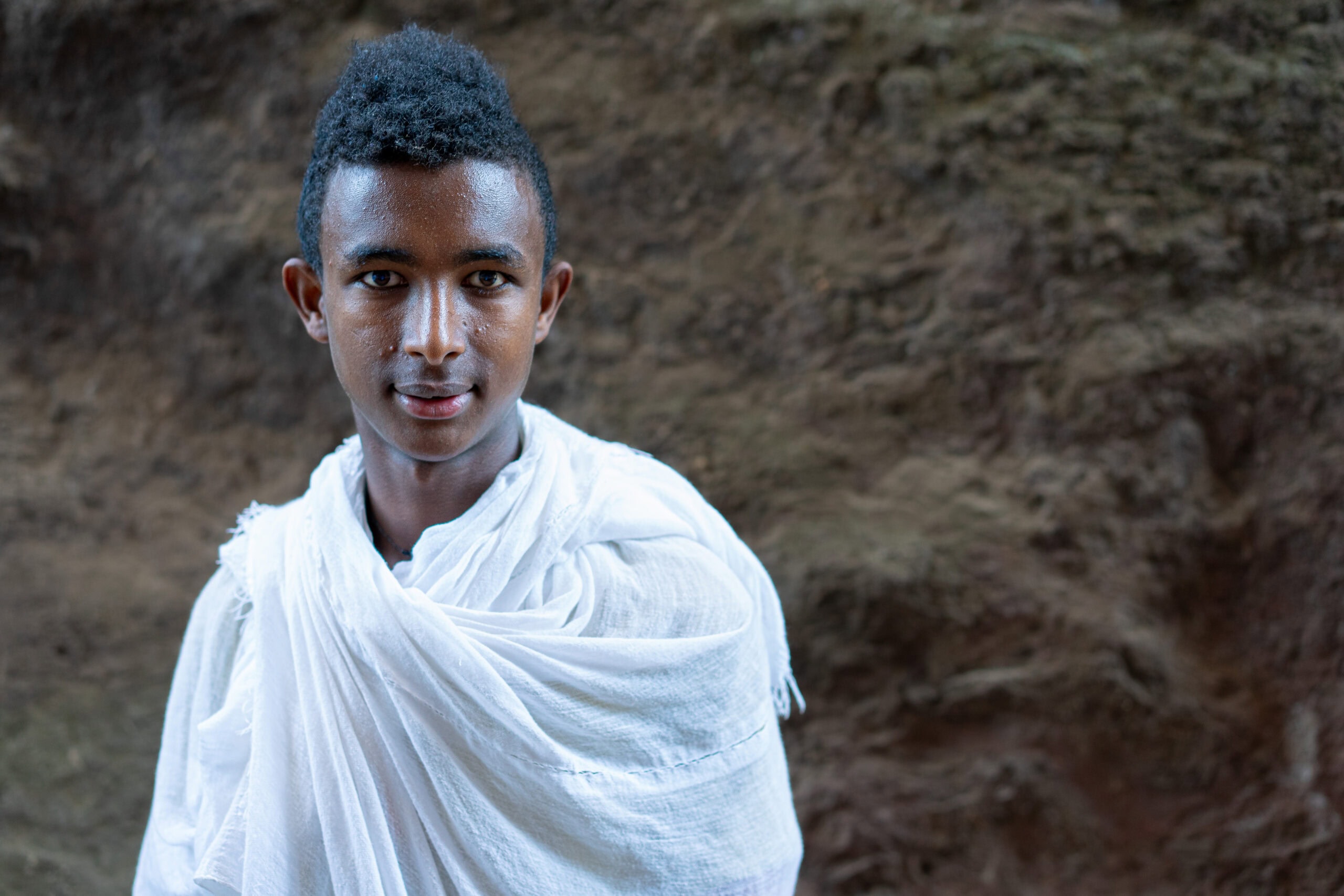 A teenage boy with an afro hairstyle, dressed in a white shawl at Biet Medhane Alem