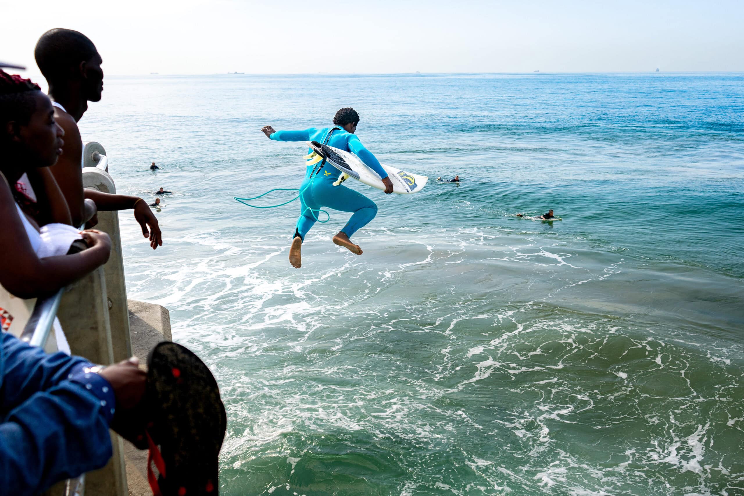 Best books to read before travelling to South Africa: A surfer jumps off the pier with his surfboard at the main beach in Durban, South Africa