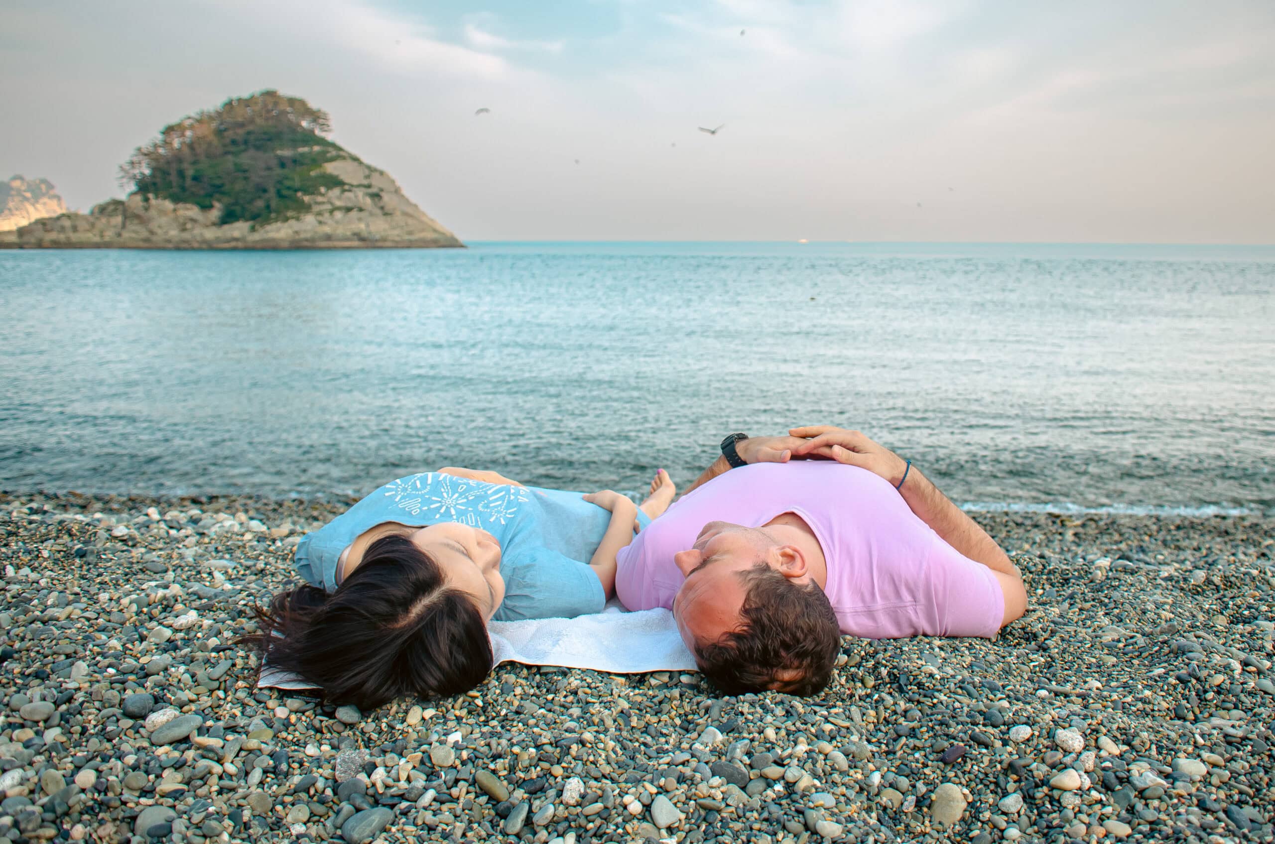 Museum of Wander Travel Blog De Wet and Jin from Museum of Wander Travel blog lying on a pebble beach on an island in South Korea