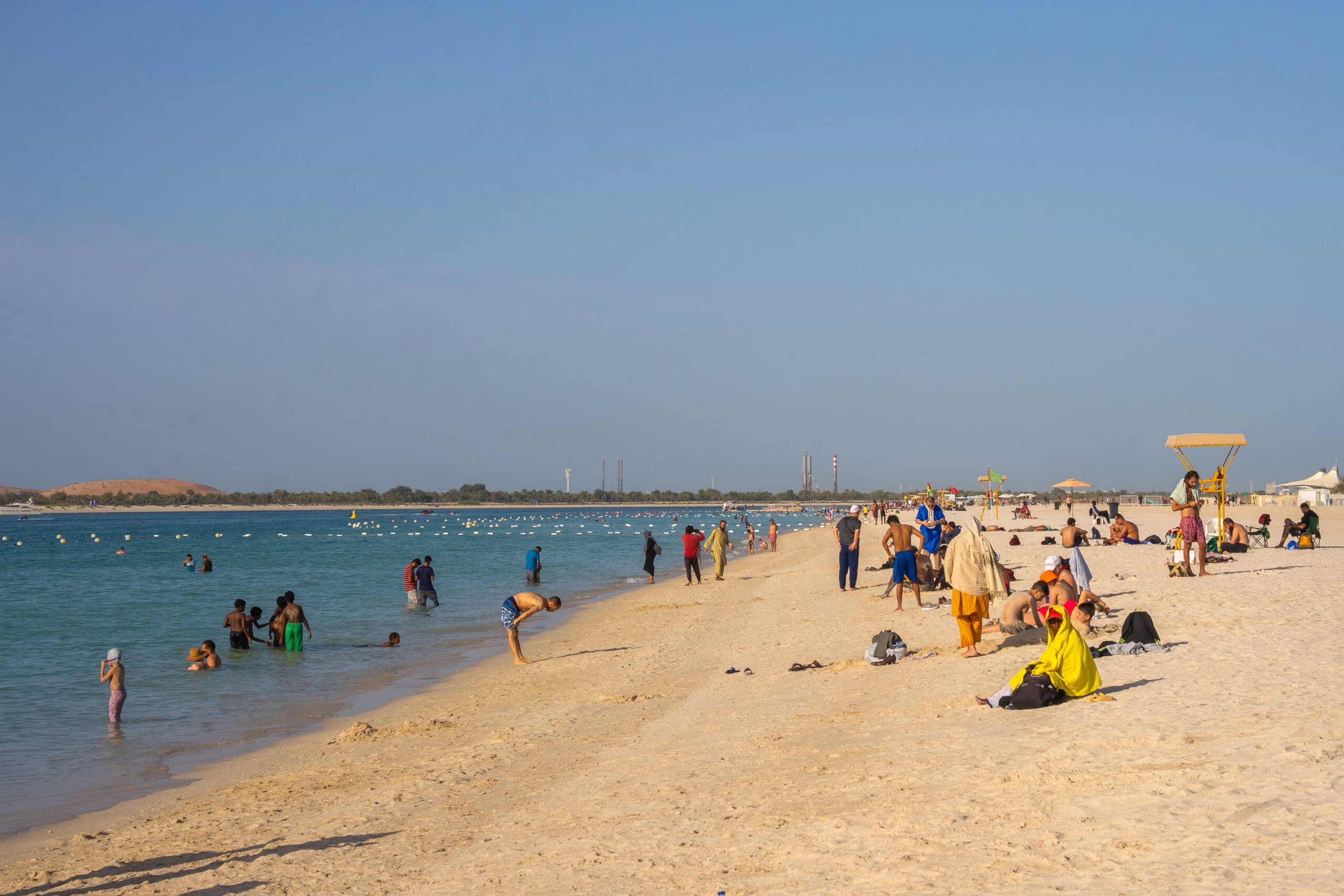 People, young and old, sunbathing and swimming at Corniche Beach, Abu Dhabi.