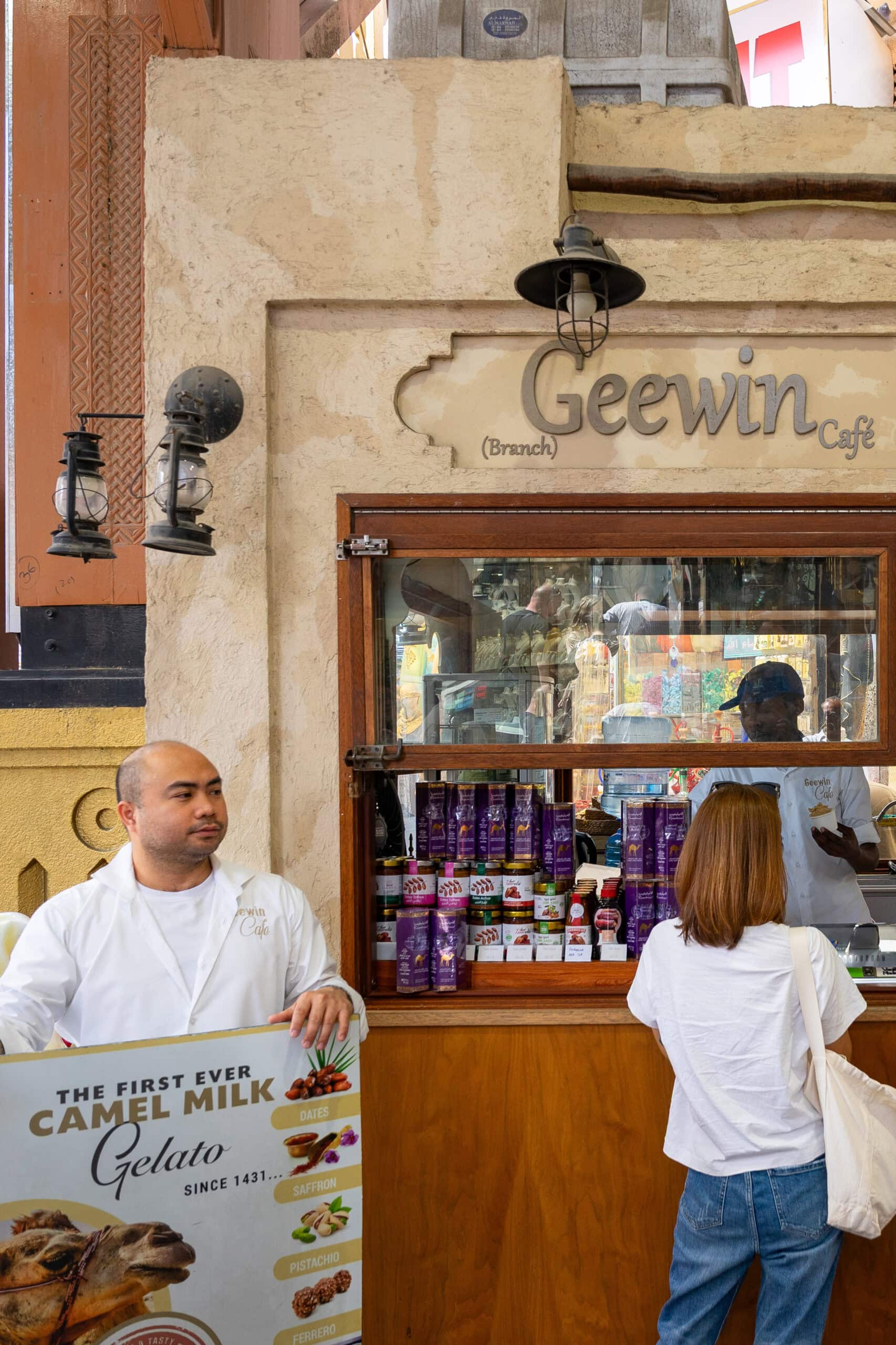 A man stands with a display advertising camel milk gelato in front of Geewin Cafe in Old Dubai