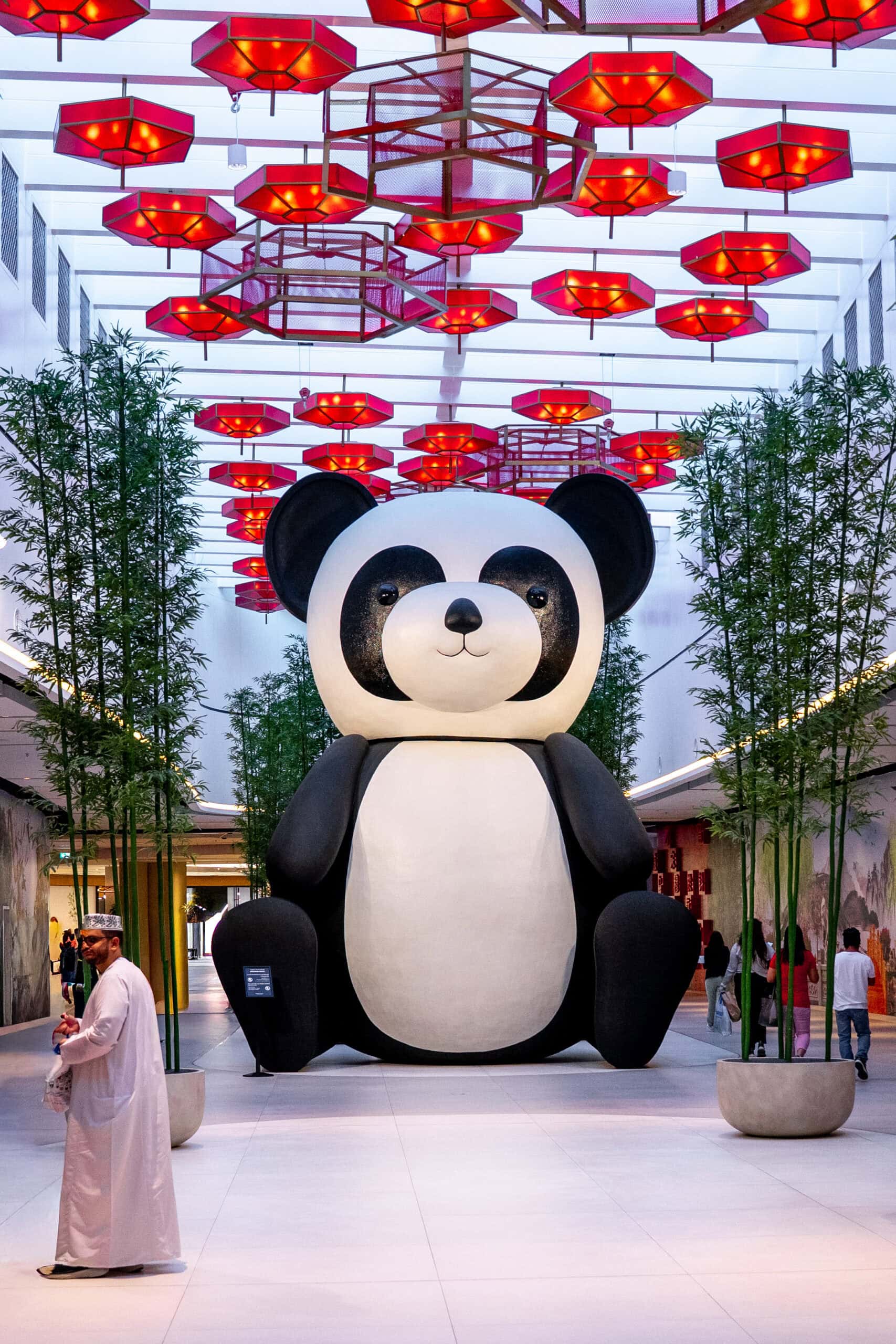 A gigantic panda sits under red umbrellas in China Town inside Dubai Mall