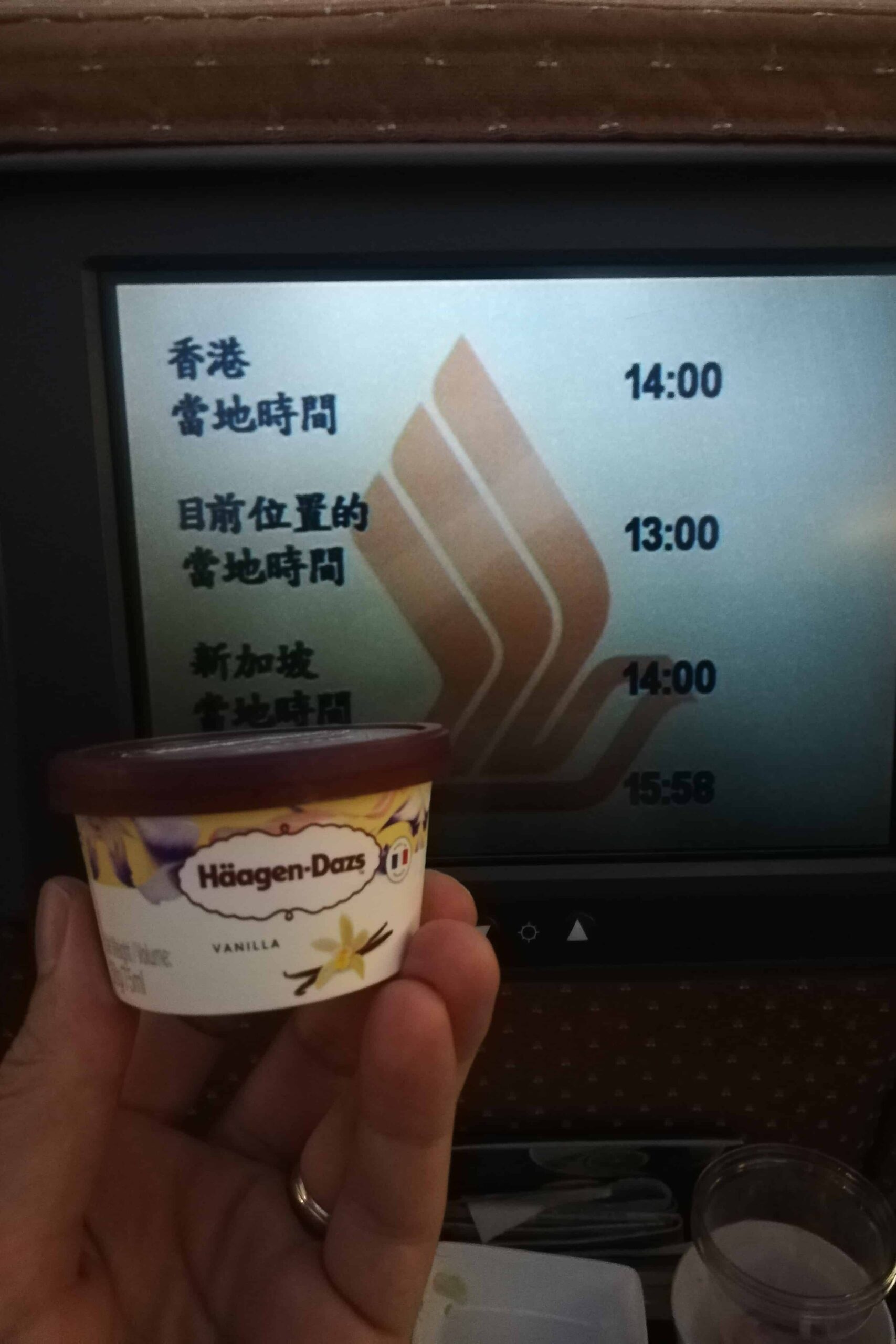 I'm holding a tub of Vanilla Haagen Dazs ice cream in front of the inflight entertainment screen on Singapore airlines flight