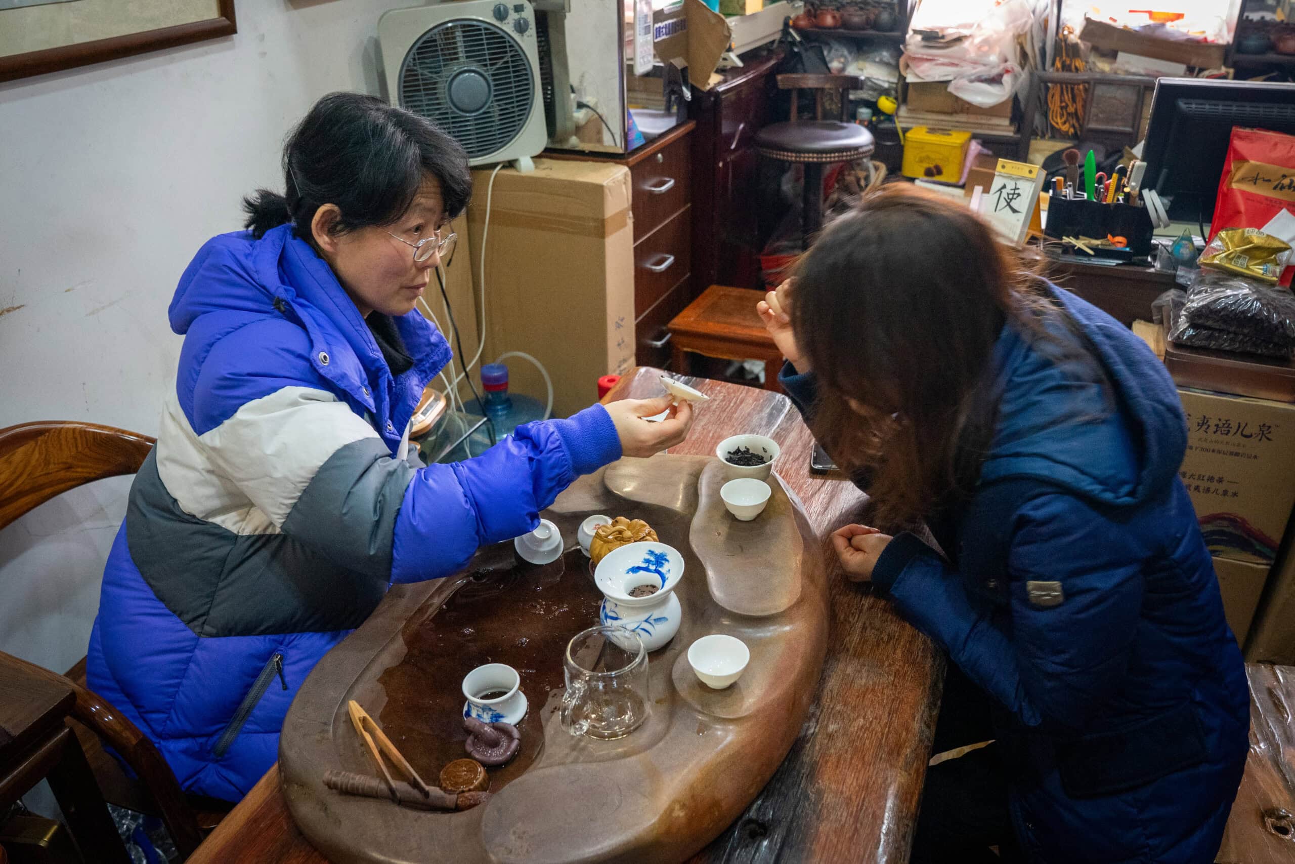 The shop owner letting Jin smell the empty tea cup