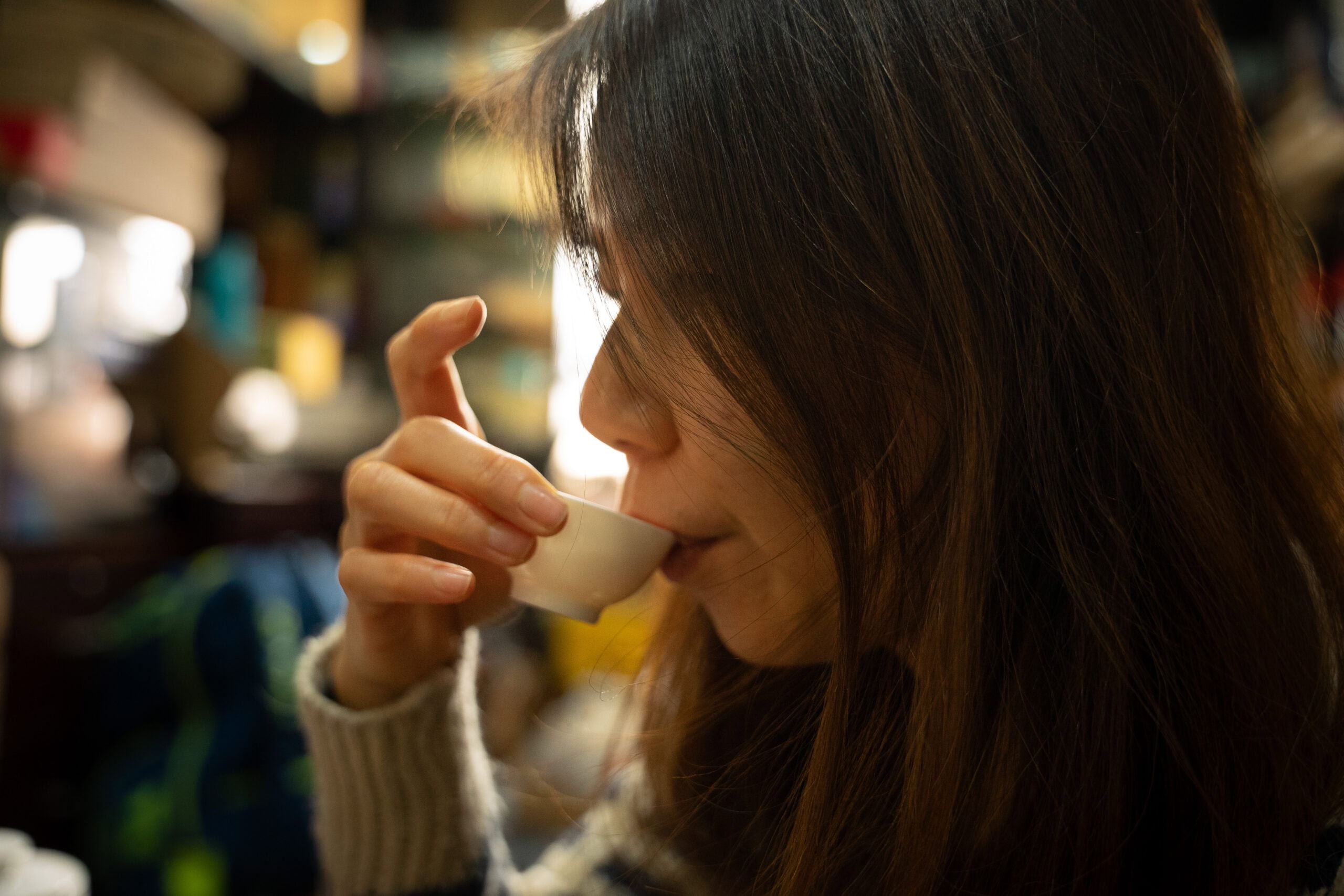 Jin takes a sip from a tiny white porcelain tea cup