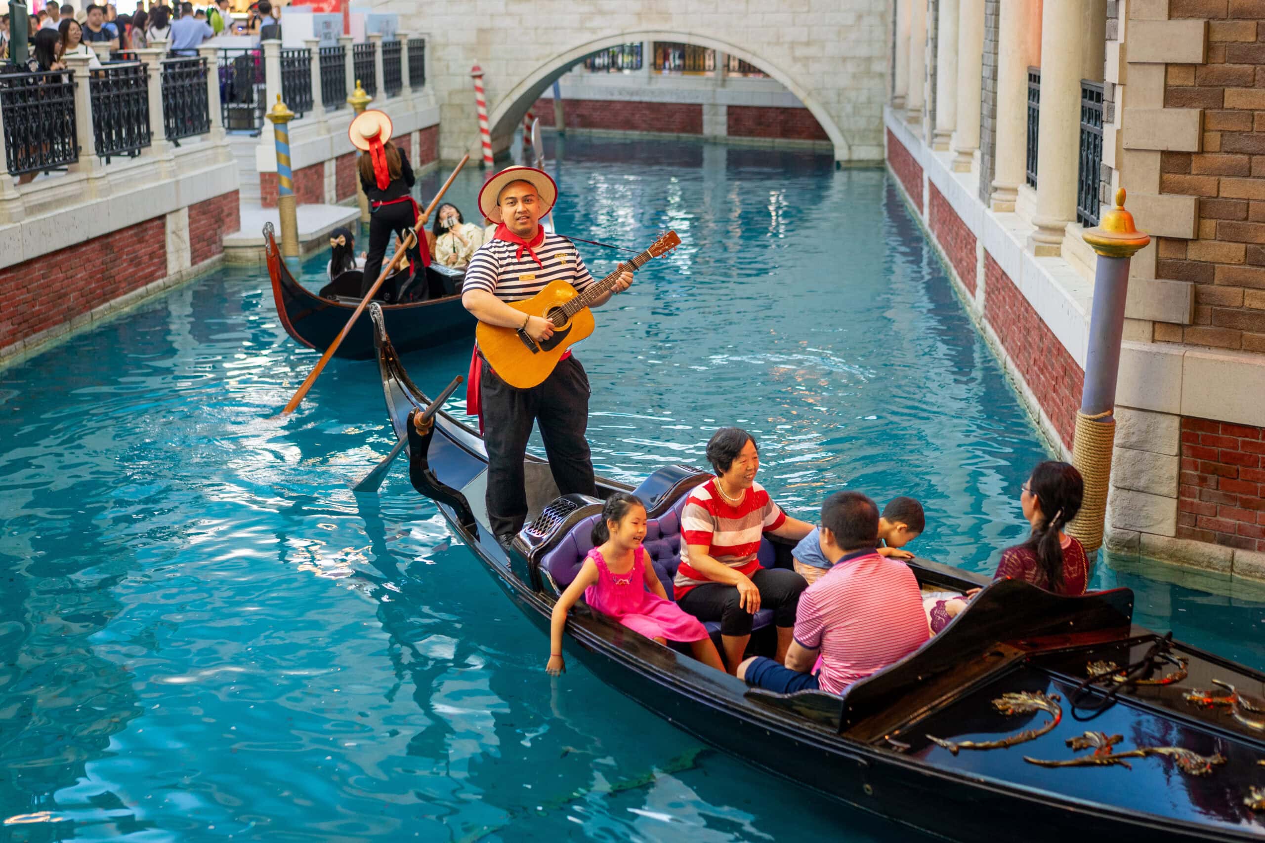 A gondola taking a family for a ride while the gondolier serenades inside the Venetian, Macau