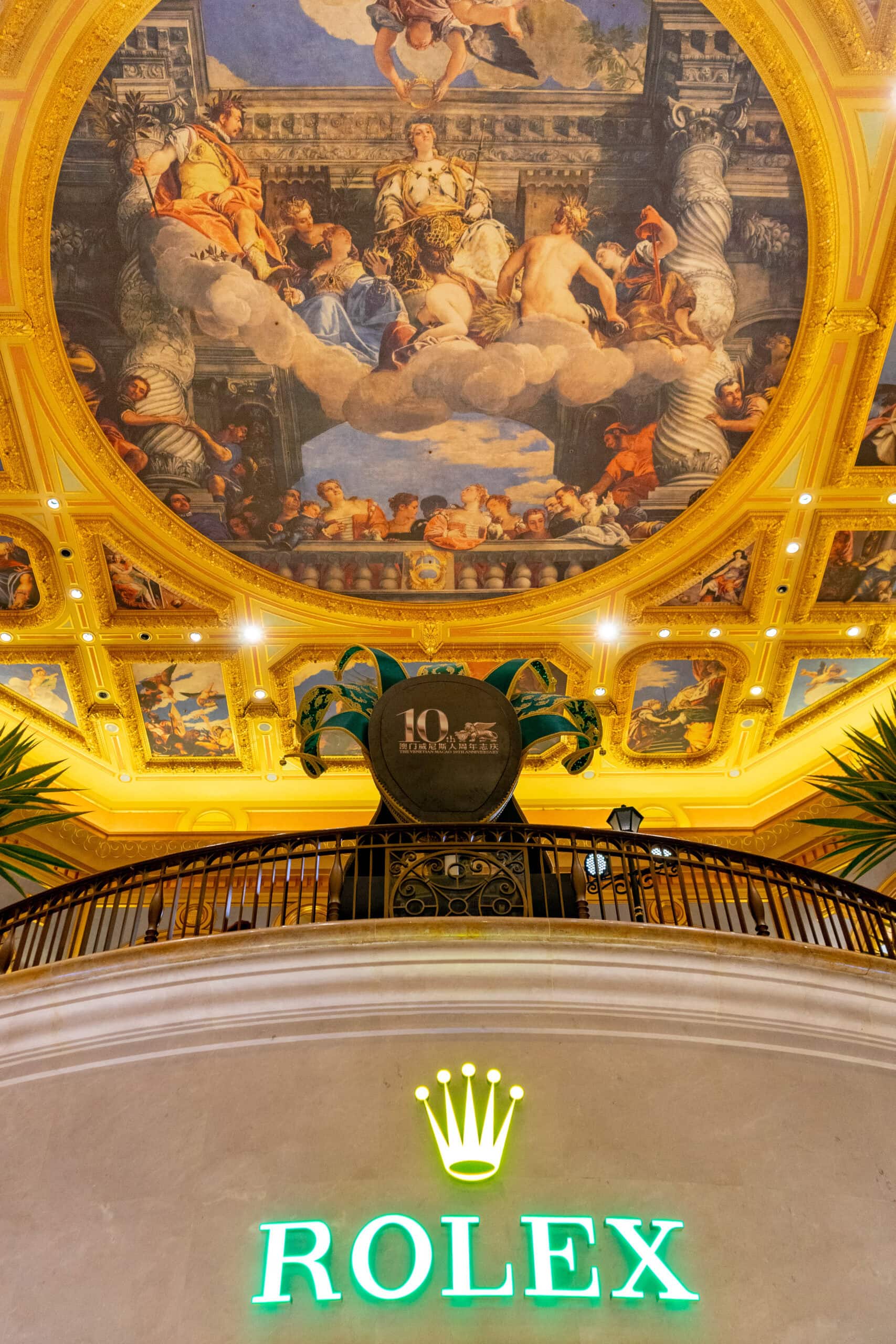 A painted dome inside the Parisian Macau, with a Rolex sign in the foreground