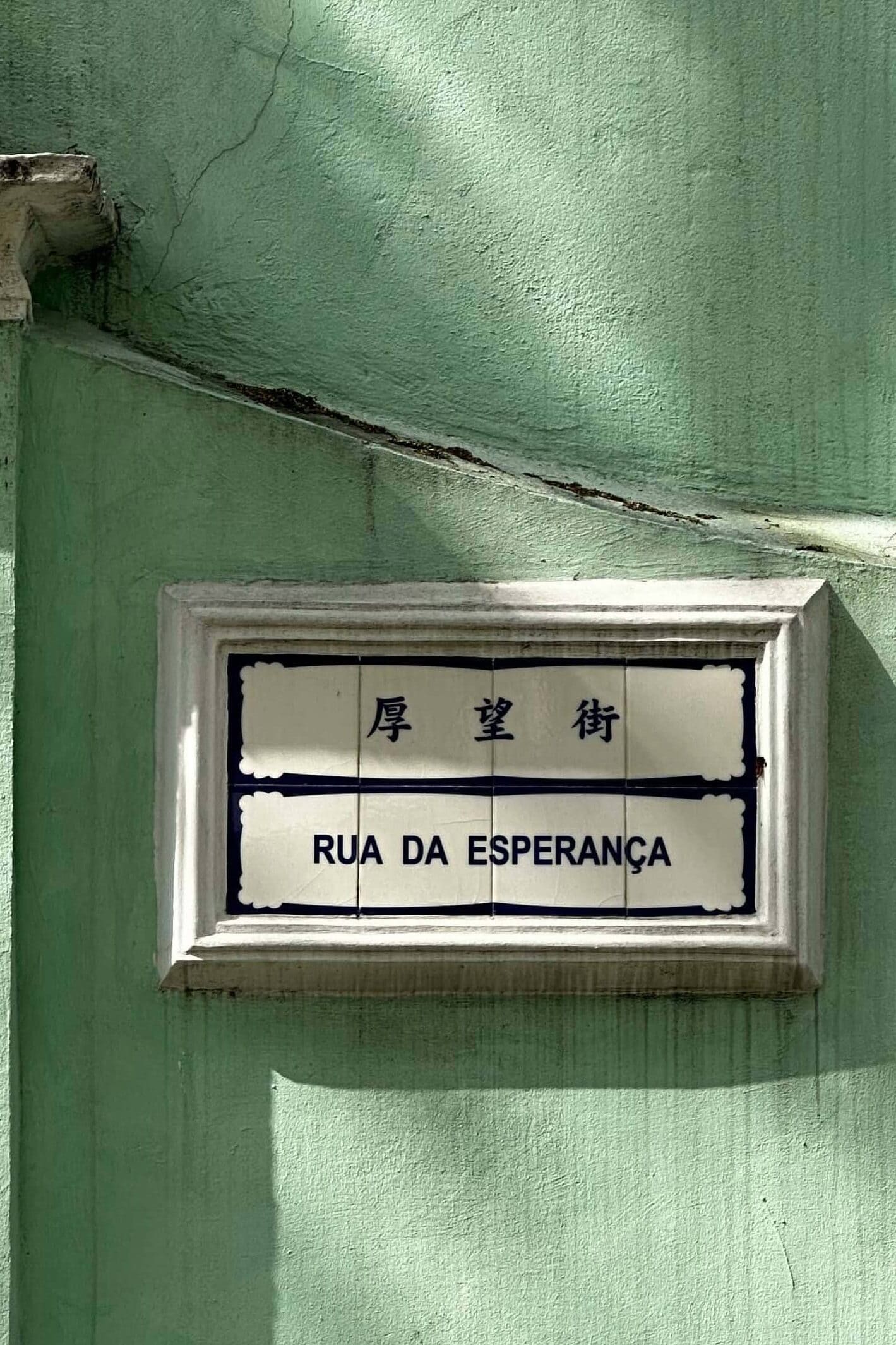 A street sign for Rua da Esperanca in Macau. It's written in blue on white porcelain tiles, in Portuguese and Chinese