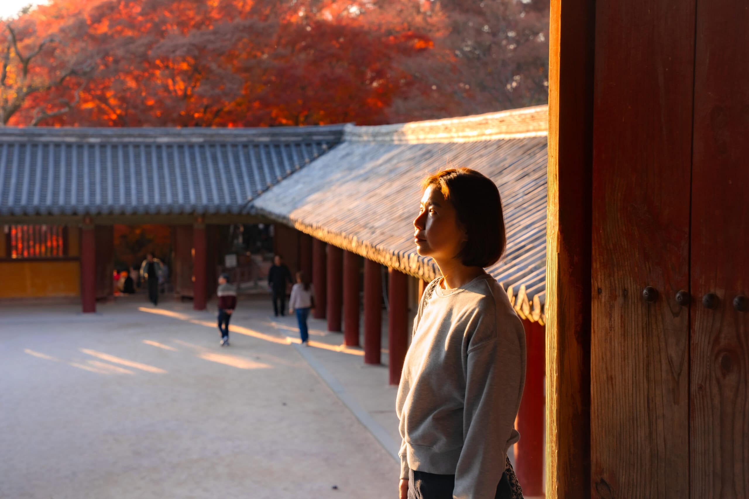 Jin standing in golden afternoon light with a courtyard in the background