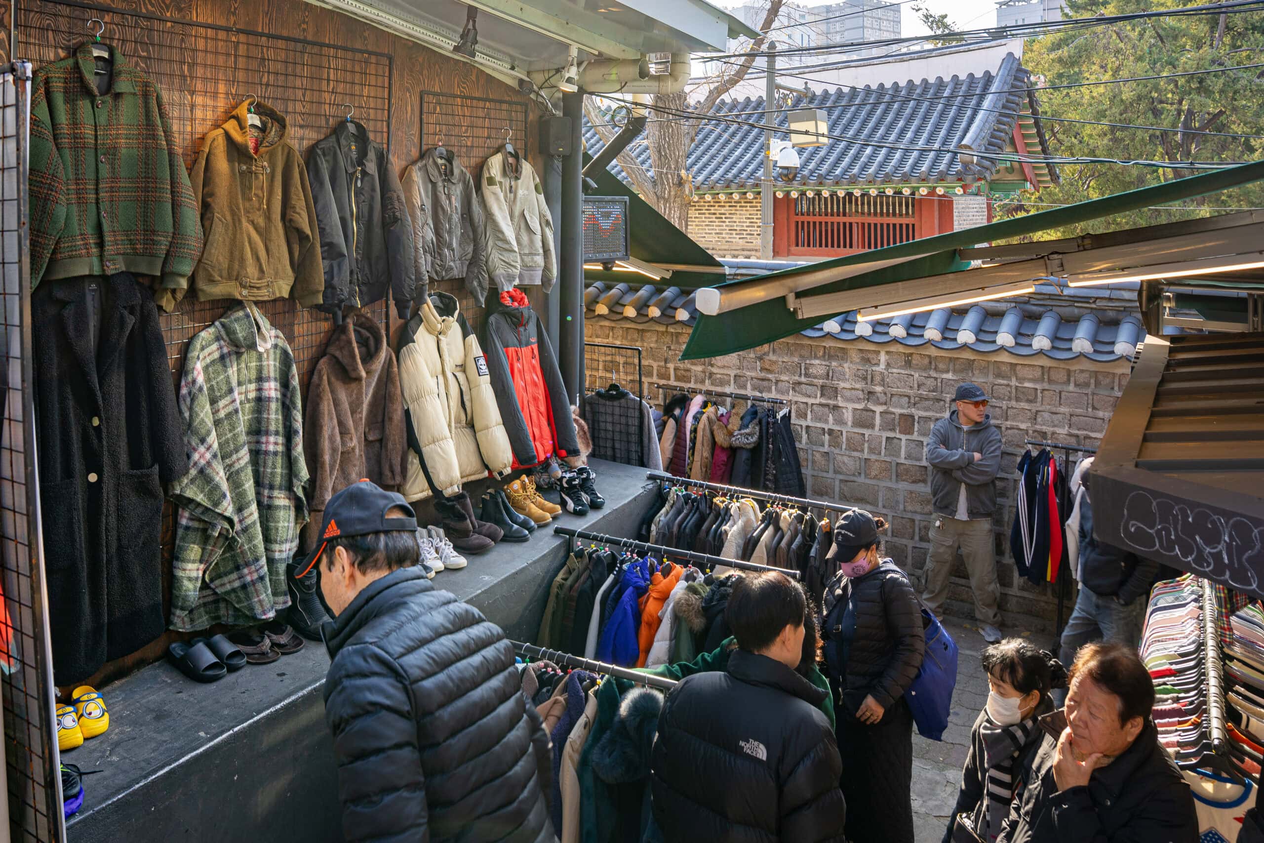 Vintage clothes hang on a hall while customers browse at Dongmyo Market in Seoul