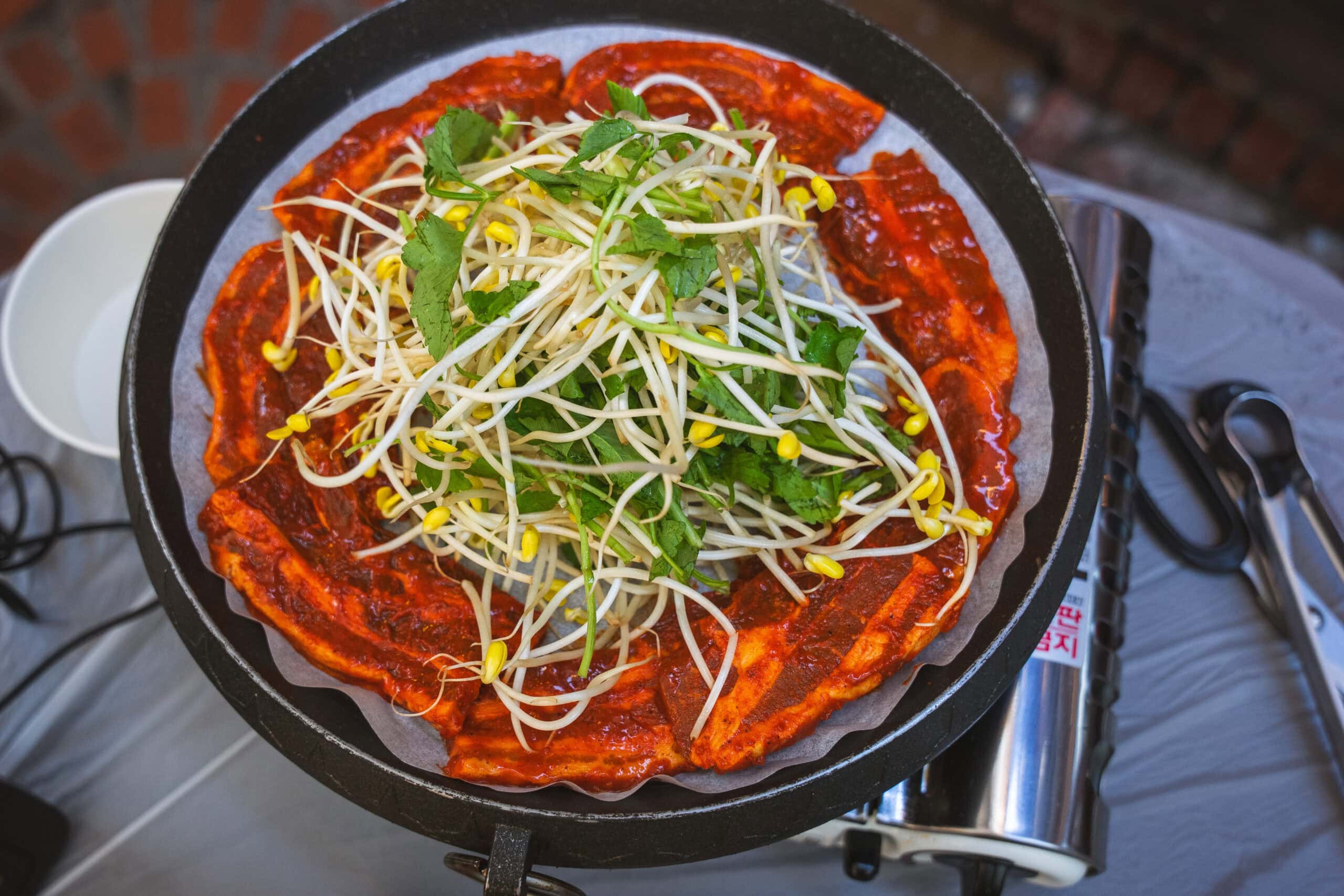 our pan with marinated pieces of pork belly (samgyeopsal) topped with bean sprouts and herbs before we started cooking 