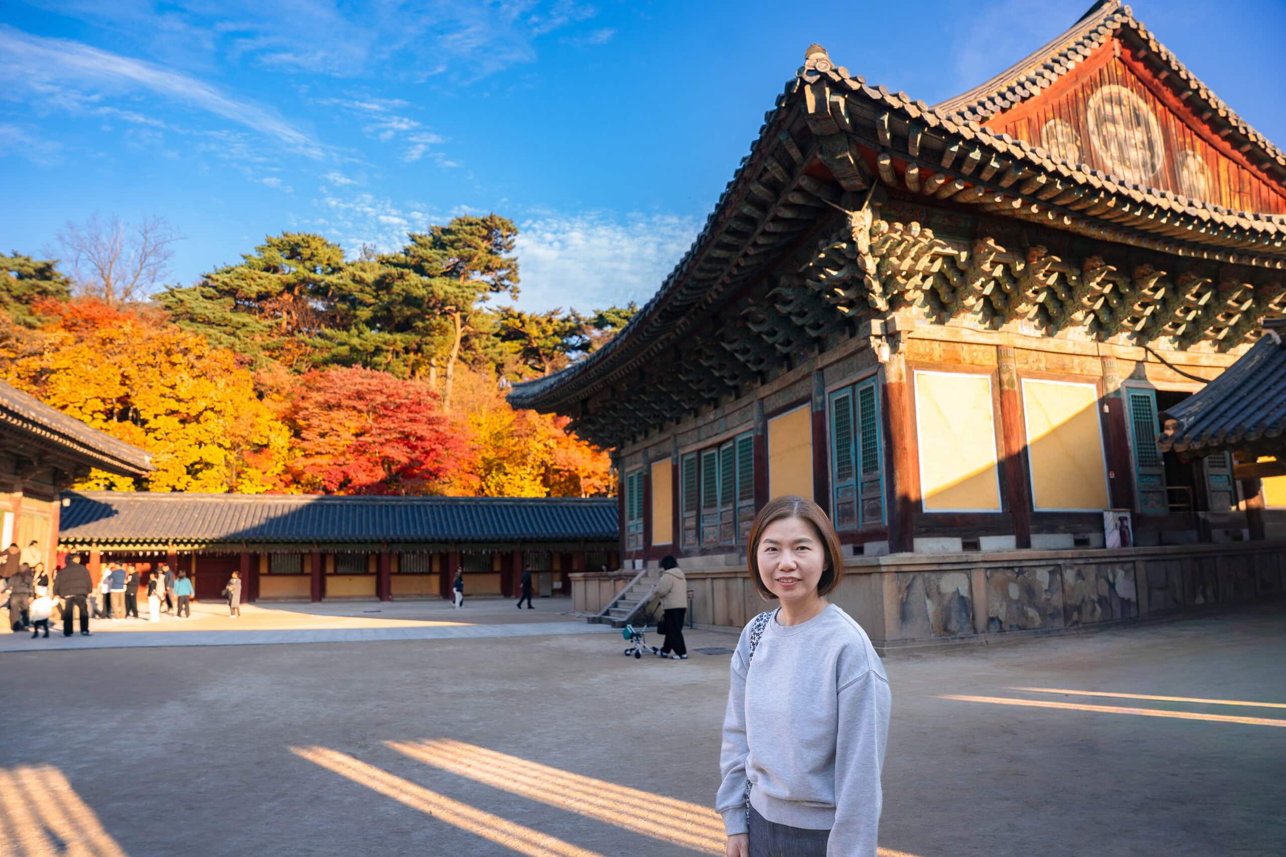 Jin smiles with the main prayer hall of Bulguksa temple behind her