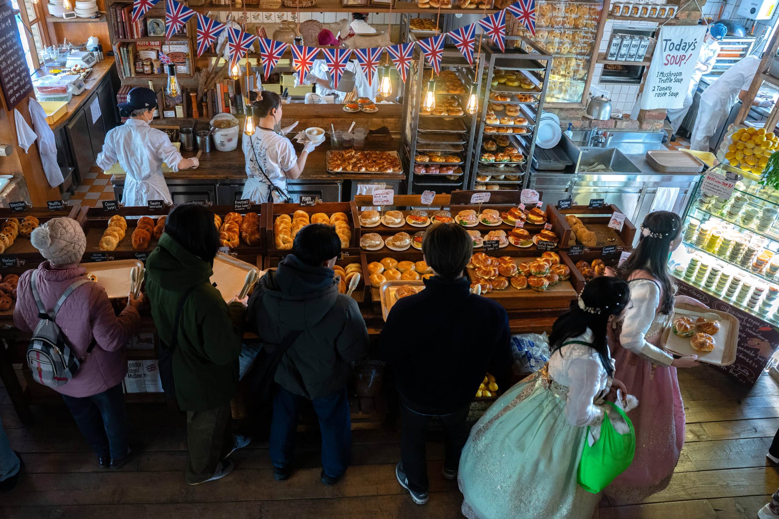 A line of people holding trays saunter along the counter looking at bagels at London Bagel Museum in central Seoul