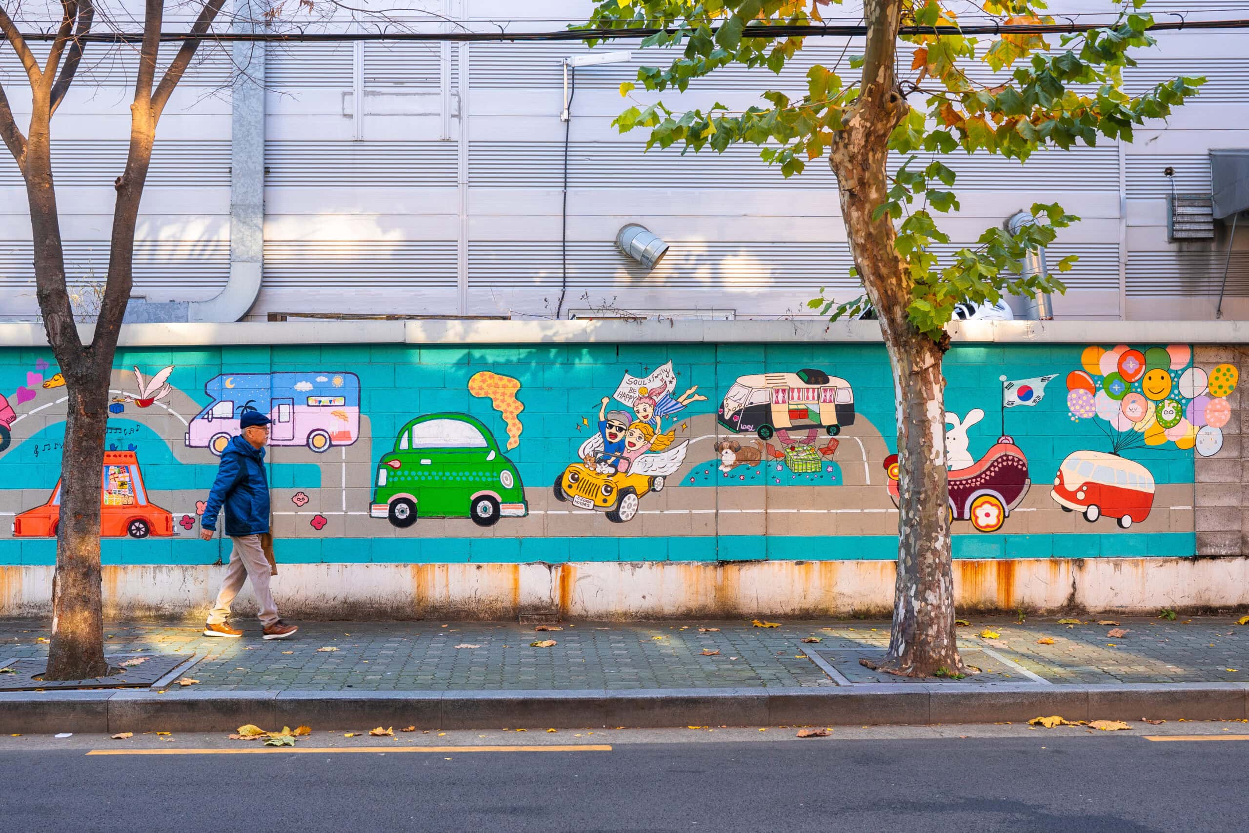 An elderly man walks along a colourful mural in Seoul