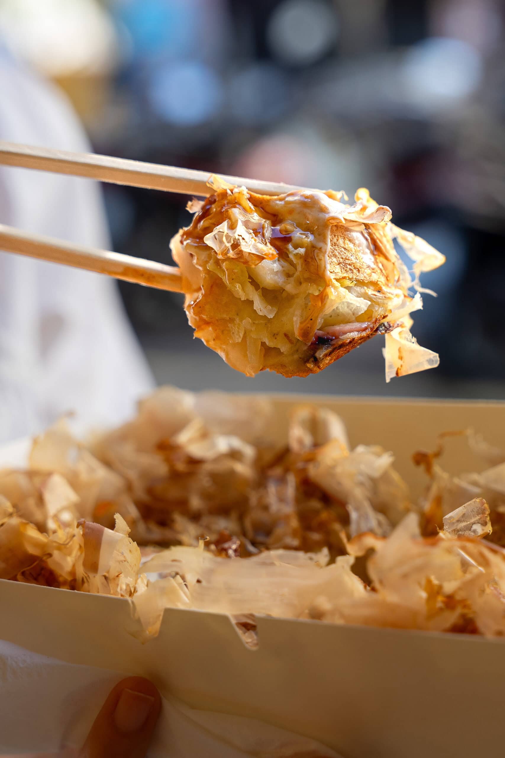 A close up of a piece of Baffle, held in the air with chop sticks