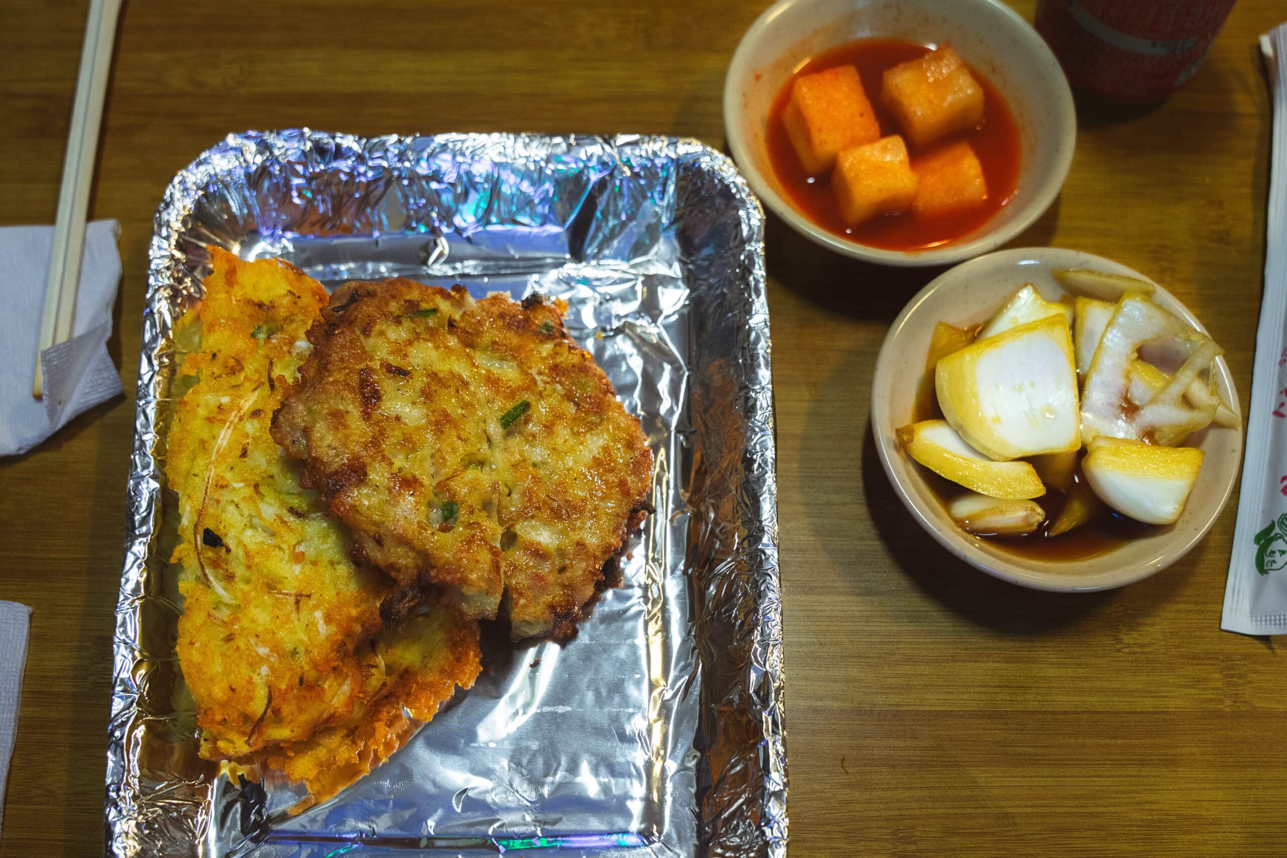 Our oreder of bindaetteak, served in an aluminium tray with radish kimchi and onions on the side