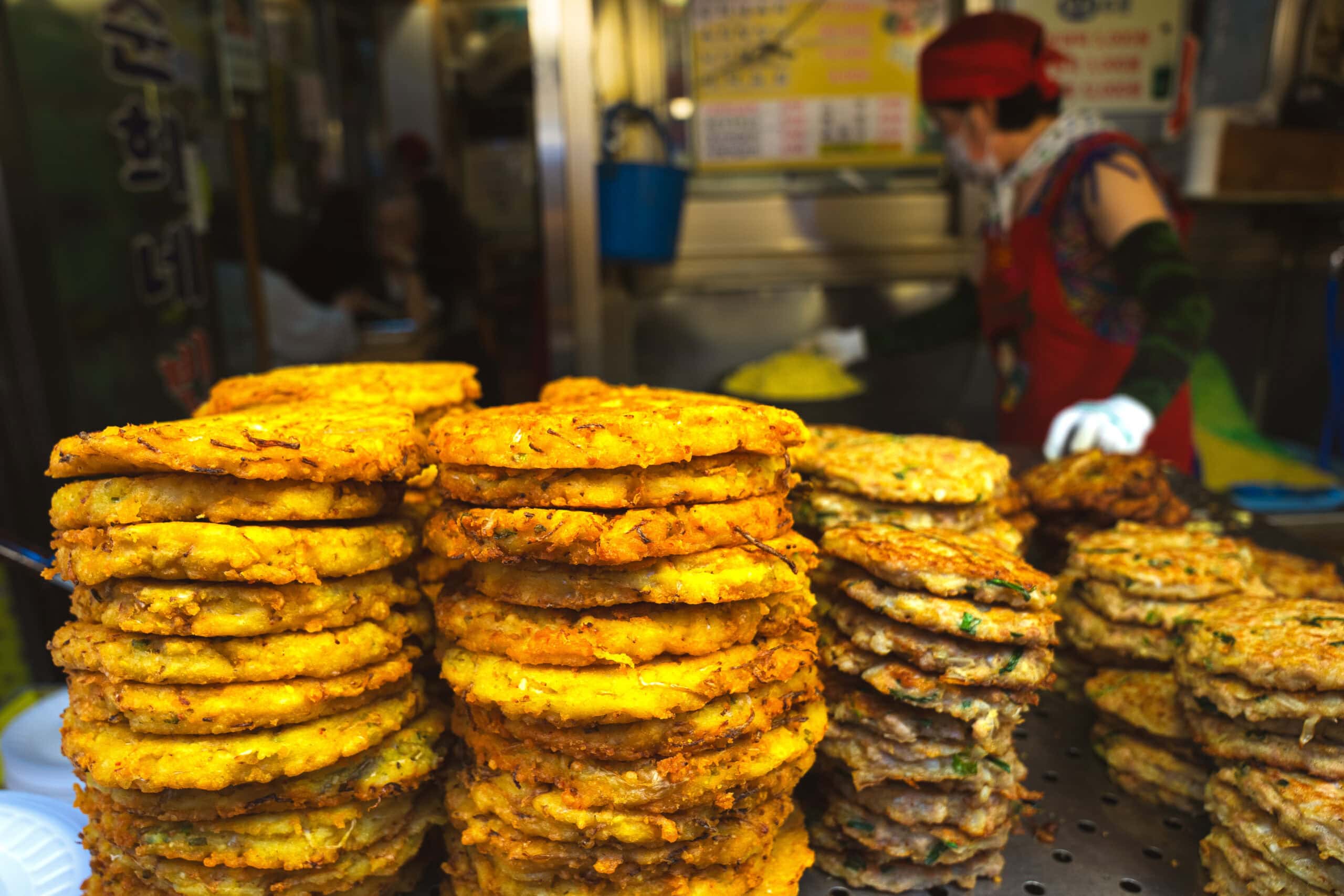 stacks of golden fried bindaetteok at gwangjang market in Seoul. 