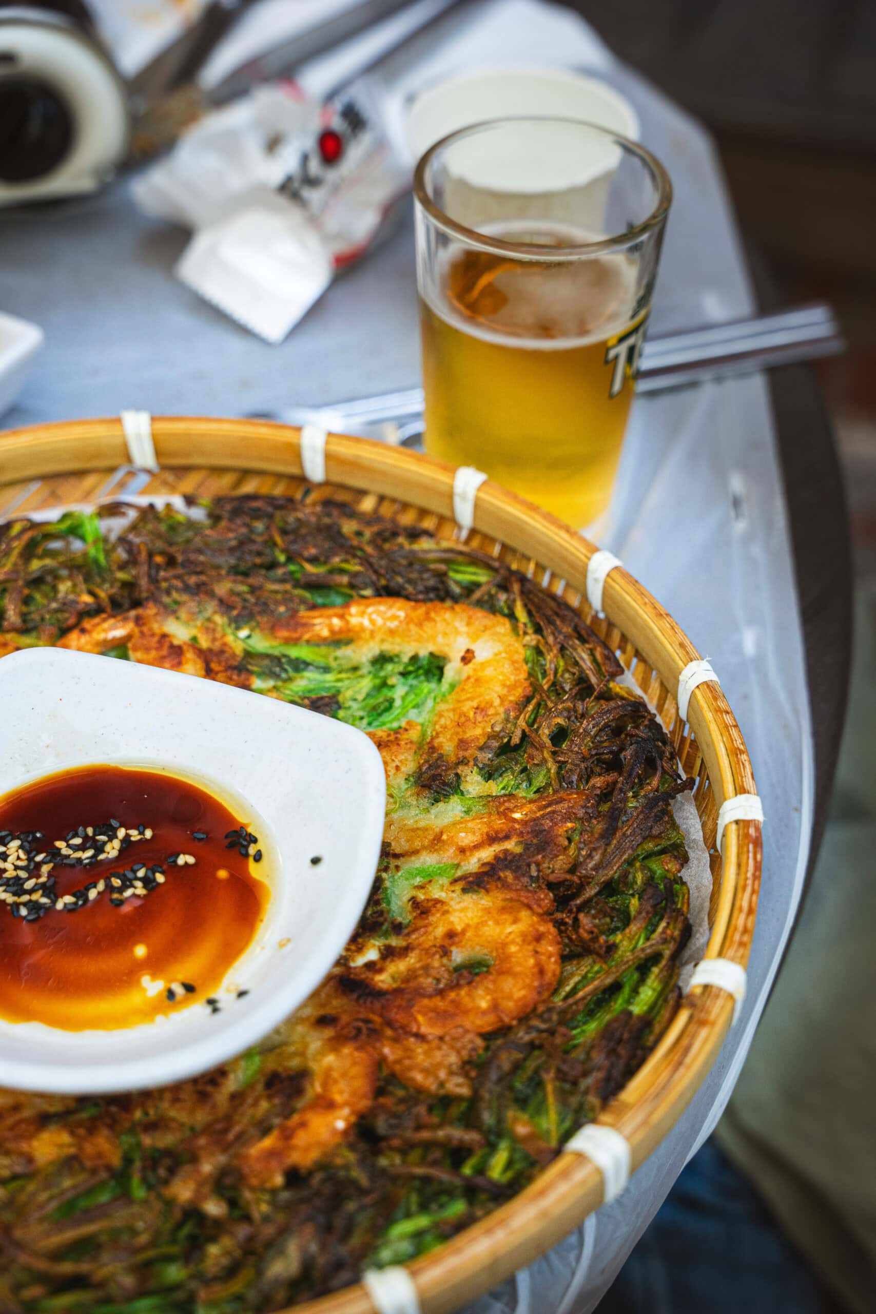 A close up of a green onion and shrimp korean pancake in a wicker tray
