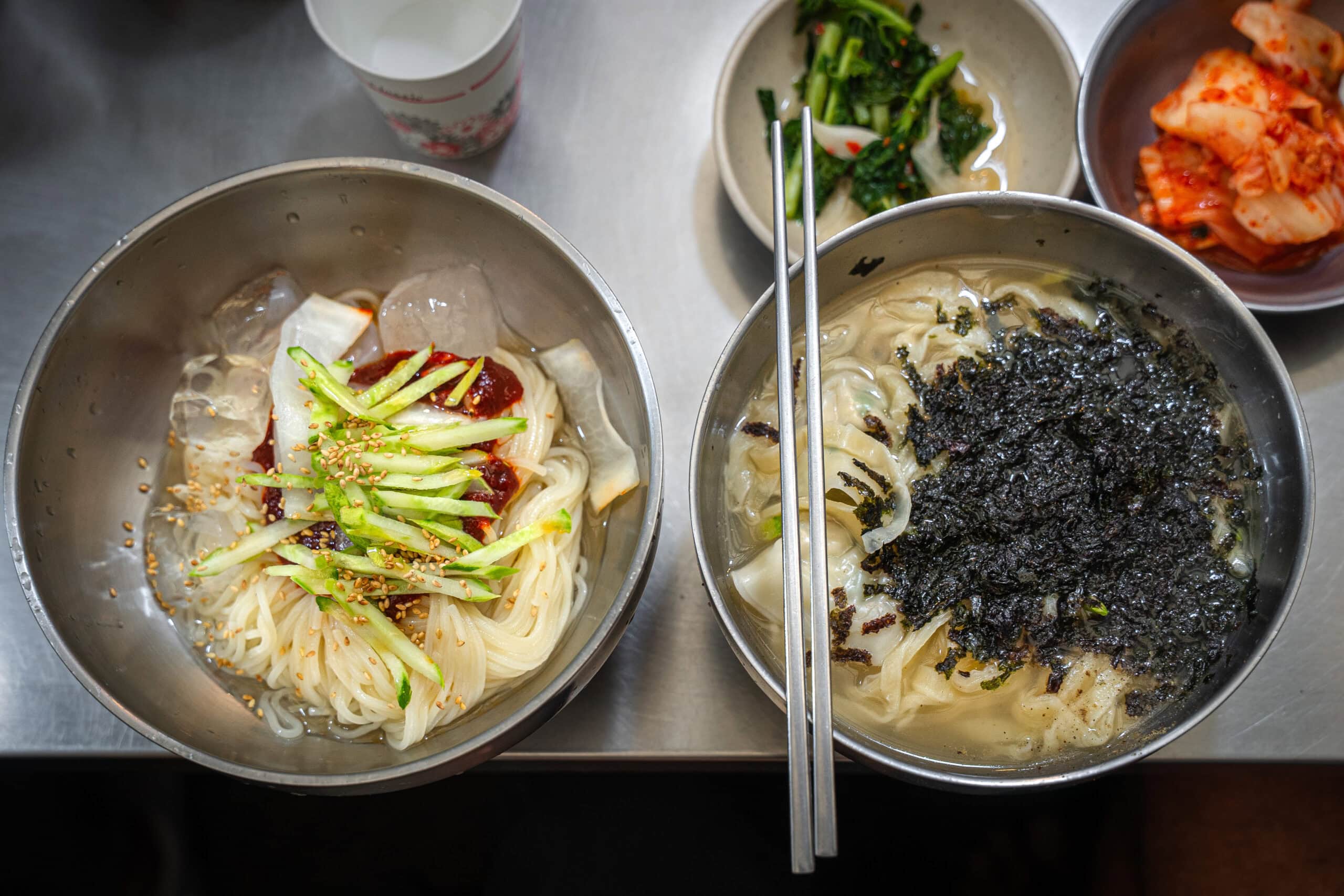 Two bowls of kalguksu and bibim-myeon illustrating what to eat in Seoul at the famous Netflix lady's market stall