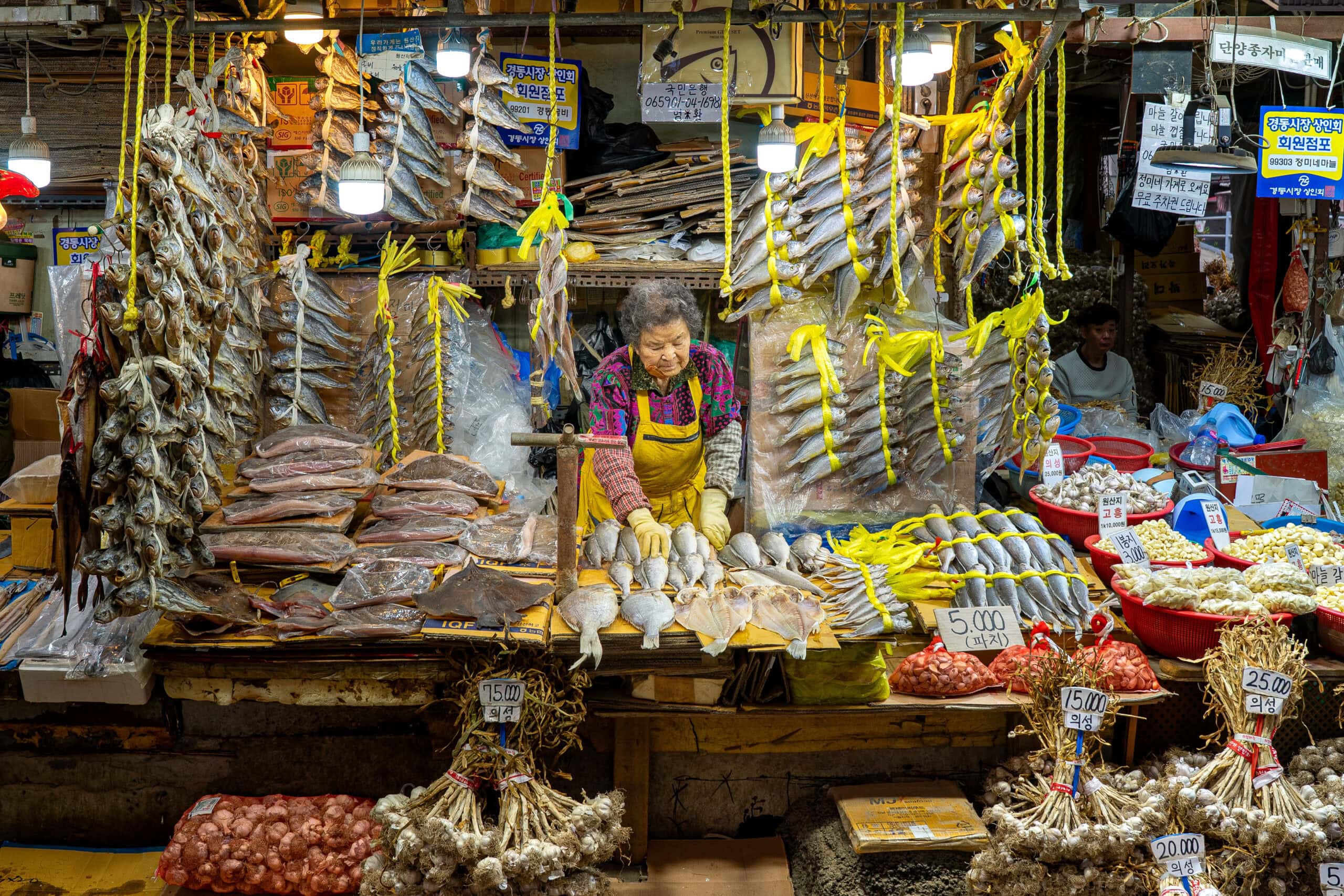 An elderly woman organizes her display of dried fish at her stall at Gyeongdong Market