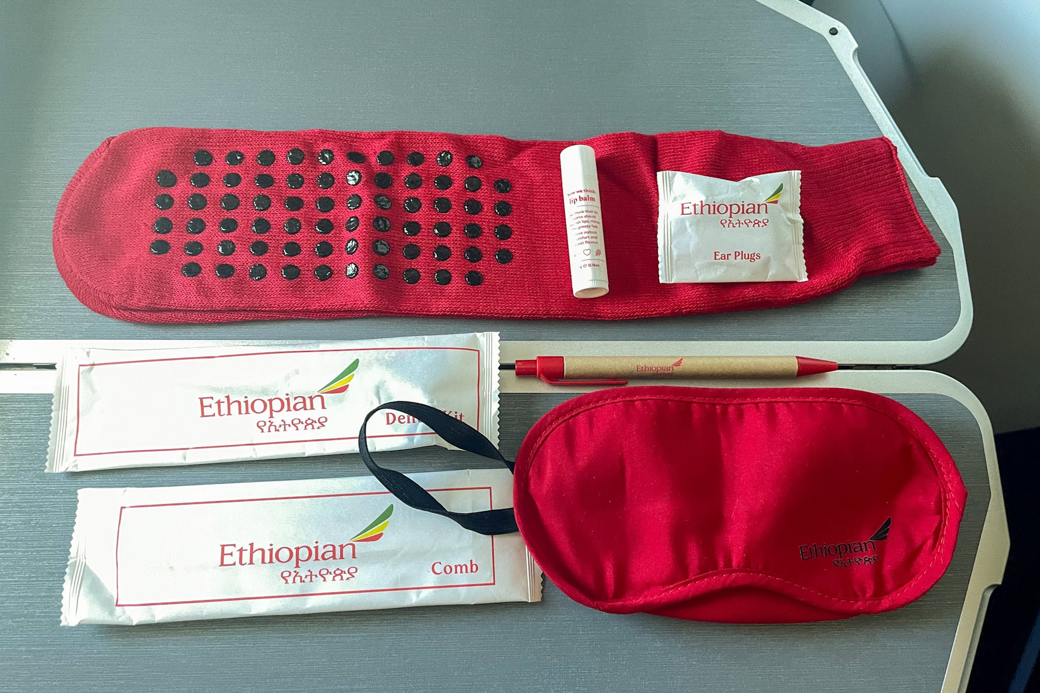 Contents of the Ethiopian Airlines Business Class Amenity Kit: red non slip socks, red sleeping mask, ear plugs, lip balm, dental kit, comb, and a pen