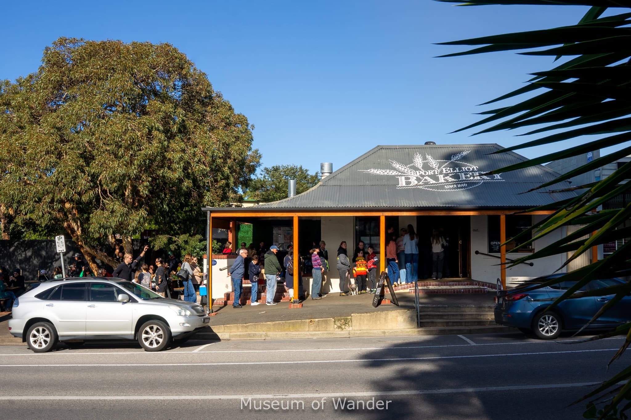 A long line standing outside Port Elliot Bakery around lunchtime. It's a clear blue sky day in July